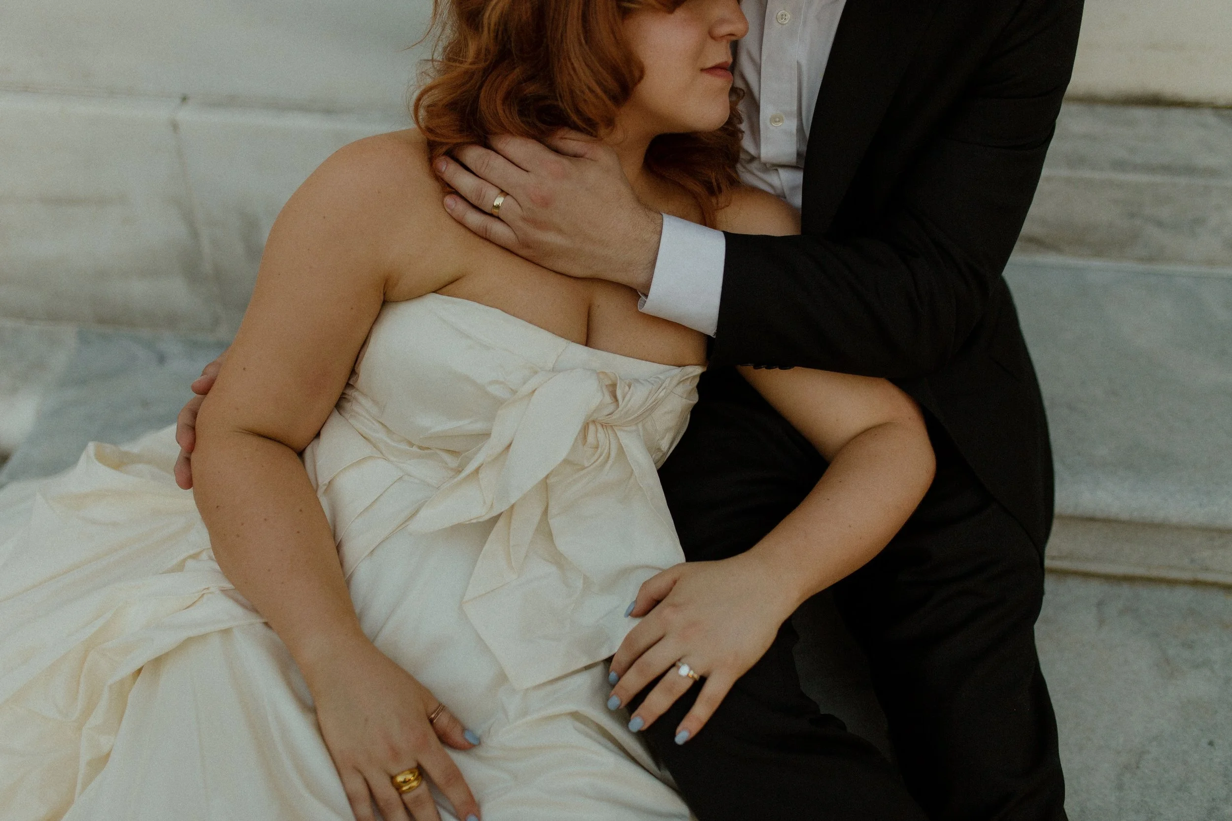 Close-up of bride leaning into groom’s chest as his arm wraps around her, capturing a quiet and intimate connection.