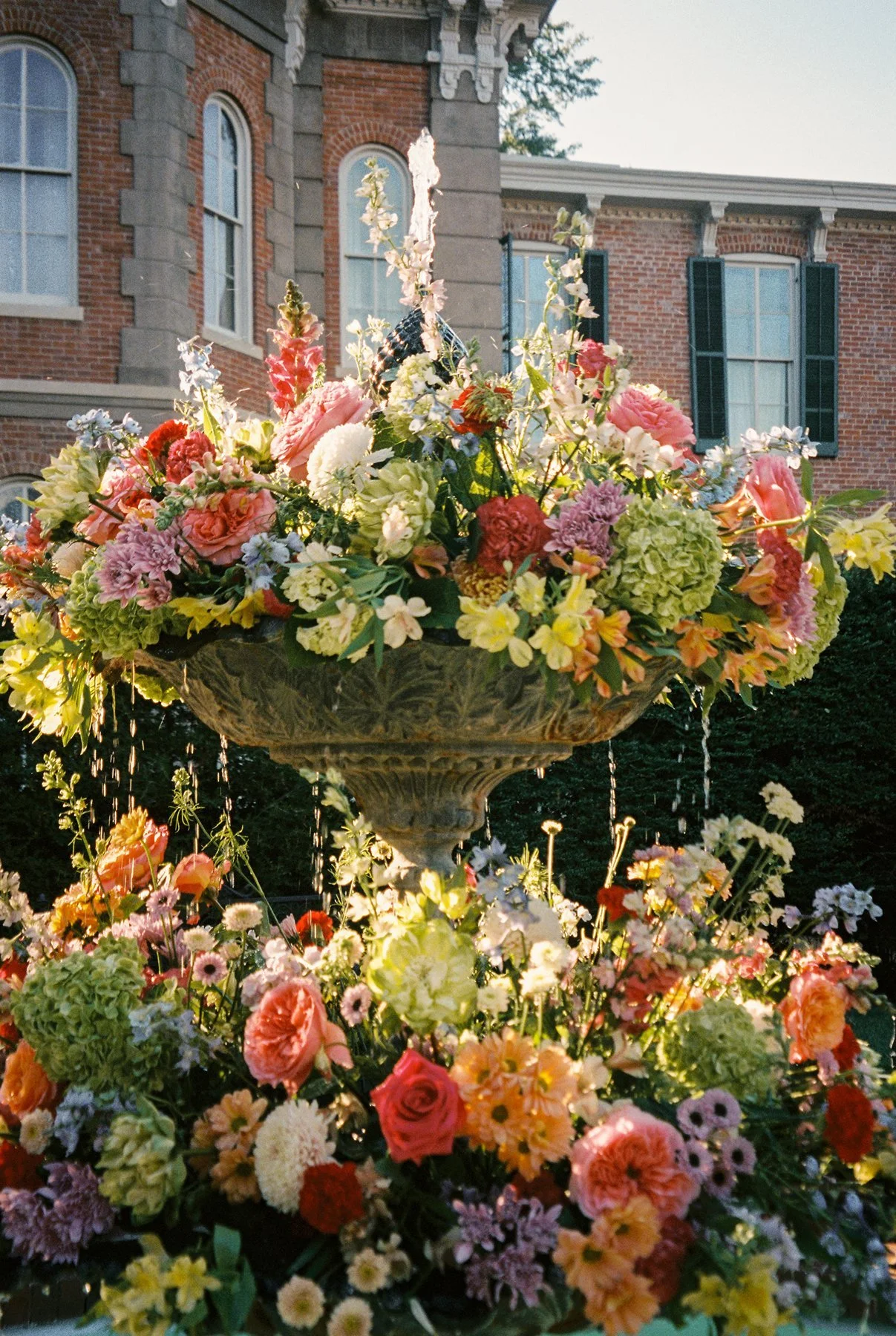 lush overflowing floral fountain installation in front of historic estate, colorful blooms cascading in the garden of a memphis wedding venue