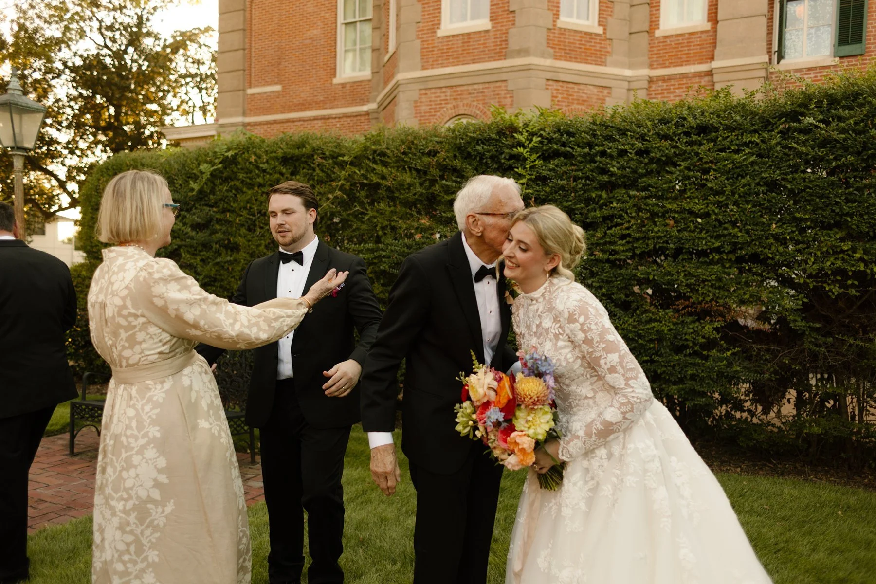 bride greeting family with a kiss on the cheek, bouquet in hand, joyful reunion unfolding at a memphis wedding venue