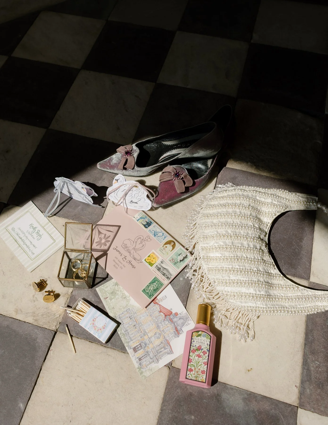 wedding flat lay with vintage-inspired details including velvet heels, stationery, perfume, and heirloom accessories