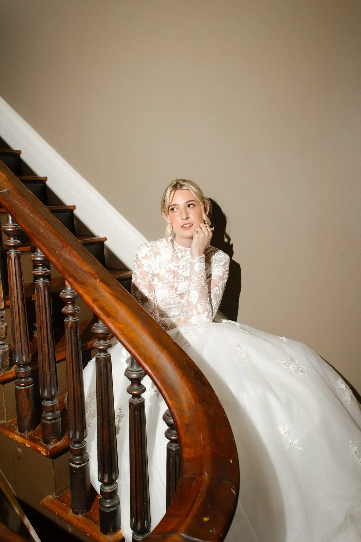 bridal portrait on staircase in lace long sleeve gown, soft light and vintage architecture creating romantic mood