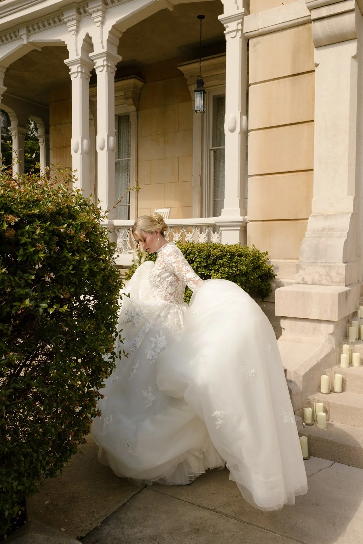 bride adjusting gown outside historic venue with soft light and architectural details surrounding her