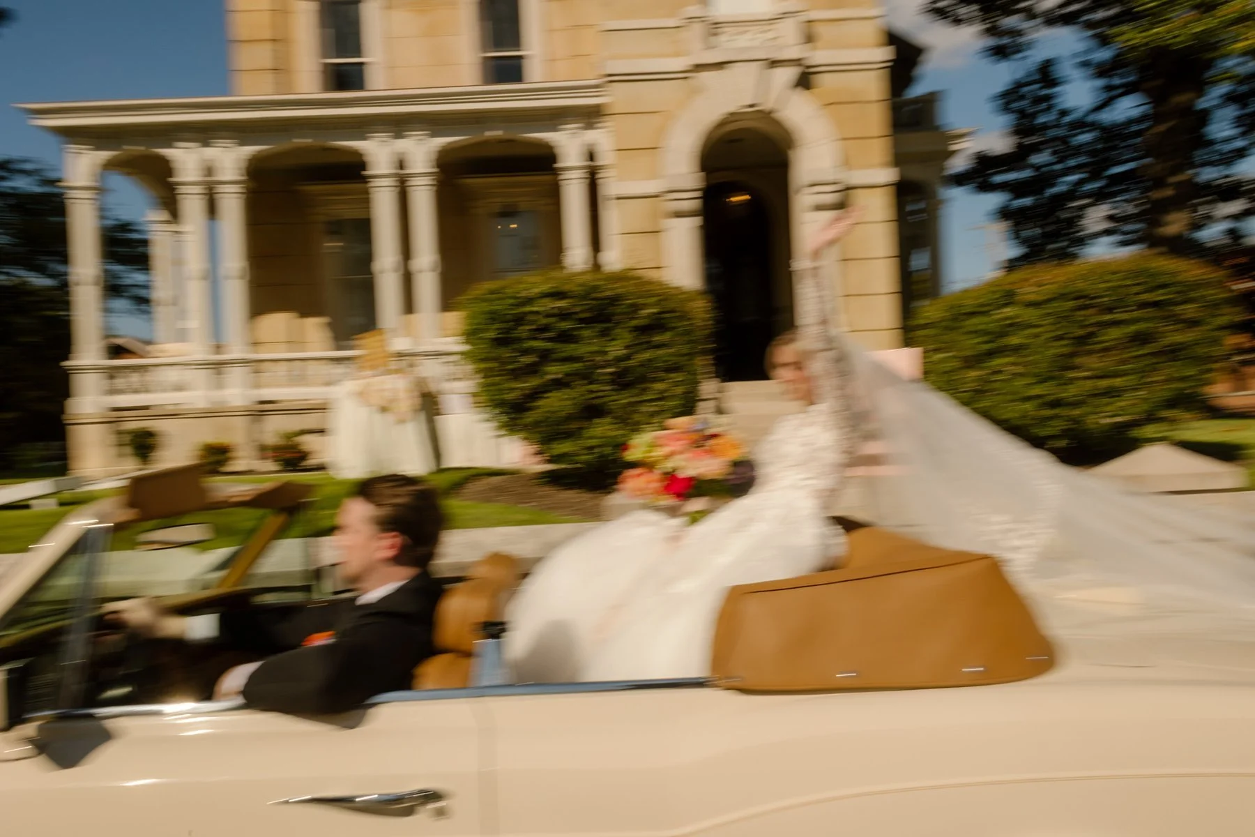 Blurry picture of bride and groom in vintage car after intimate Memphis Wedding Venues wedding at James Lee House