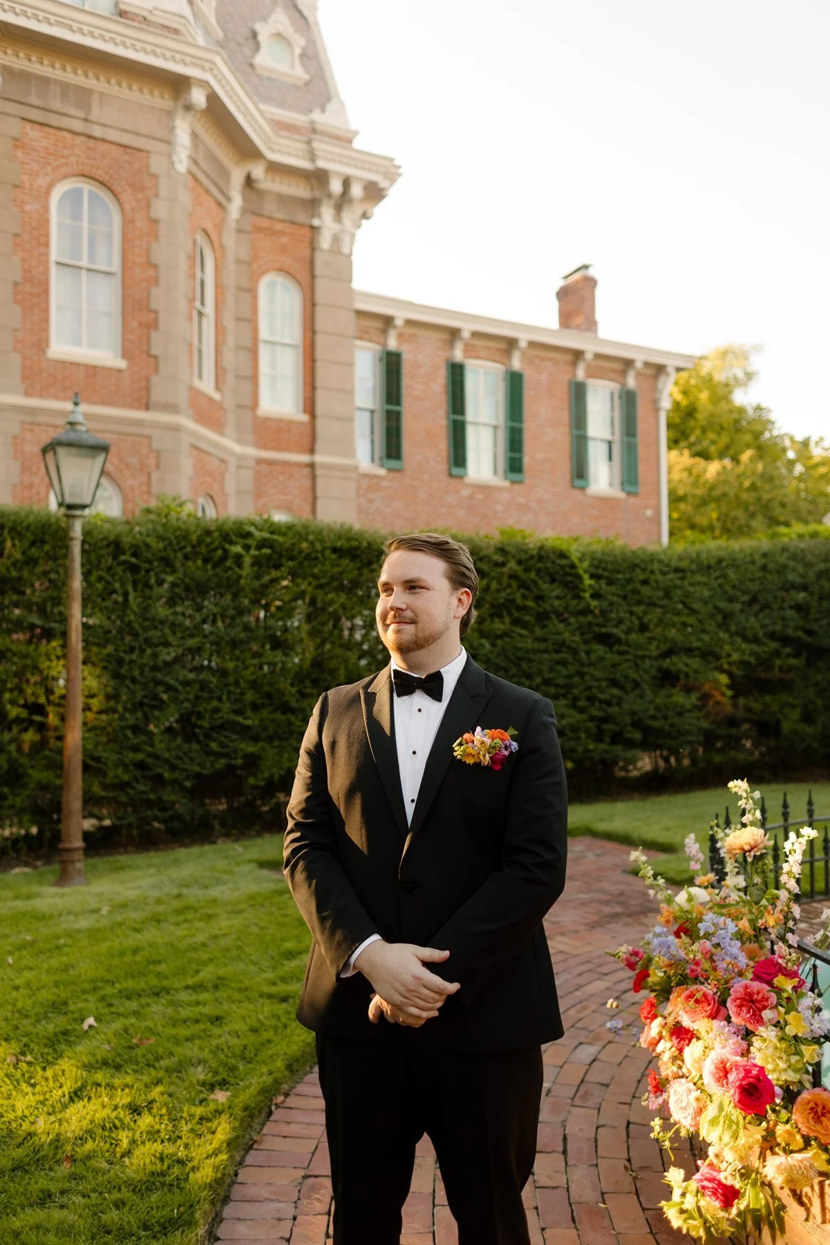groom waiting for ceremony in black tuxedo beside colorful florals at an outdoor memphis wedding venue