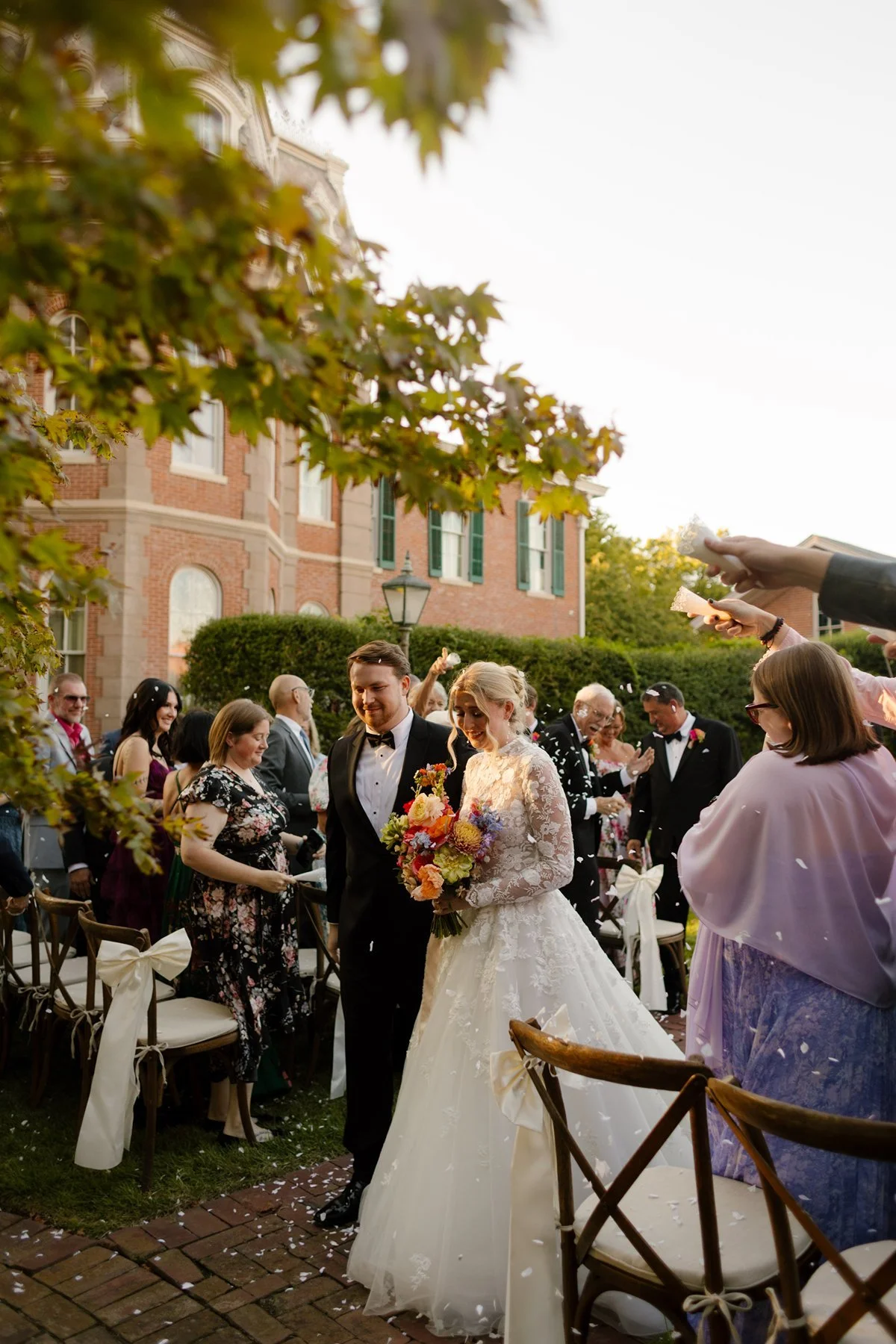 newlyweds walking down aisle as guests toss petals, joyful candid moment at a memphis wedding venue