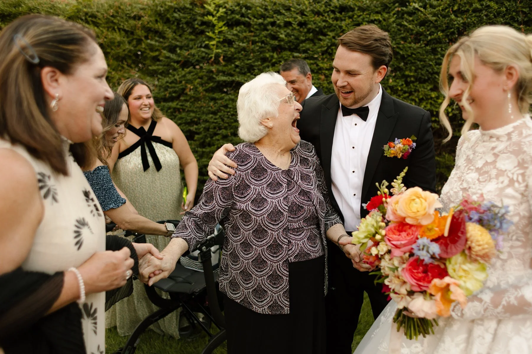groom embracing grandmother while family gathers around, emotional candid moment at a memphis wedding venue