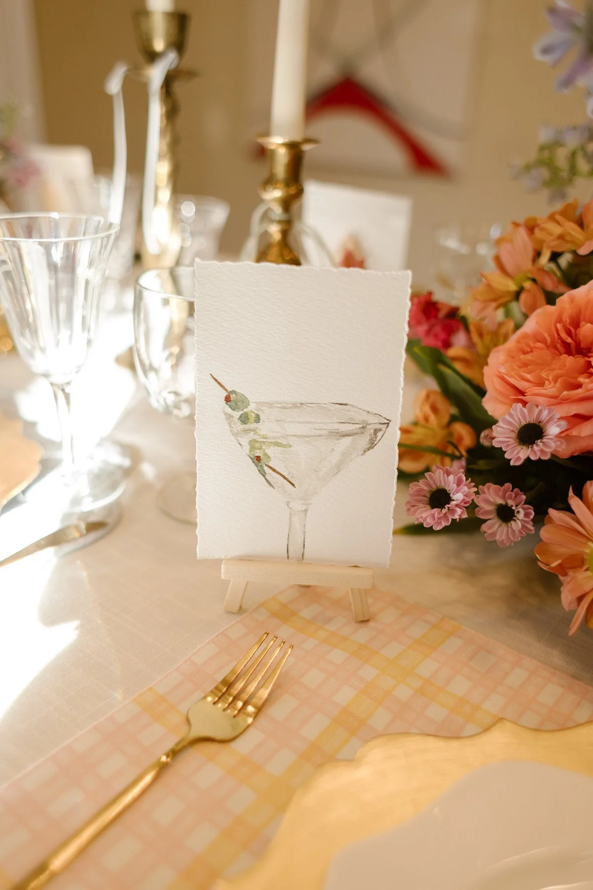 watercolor cocktail illustration place card surrounded by soft florals and candlelight at reception