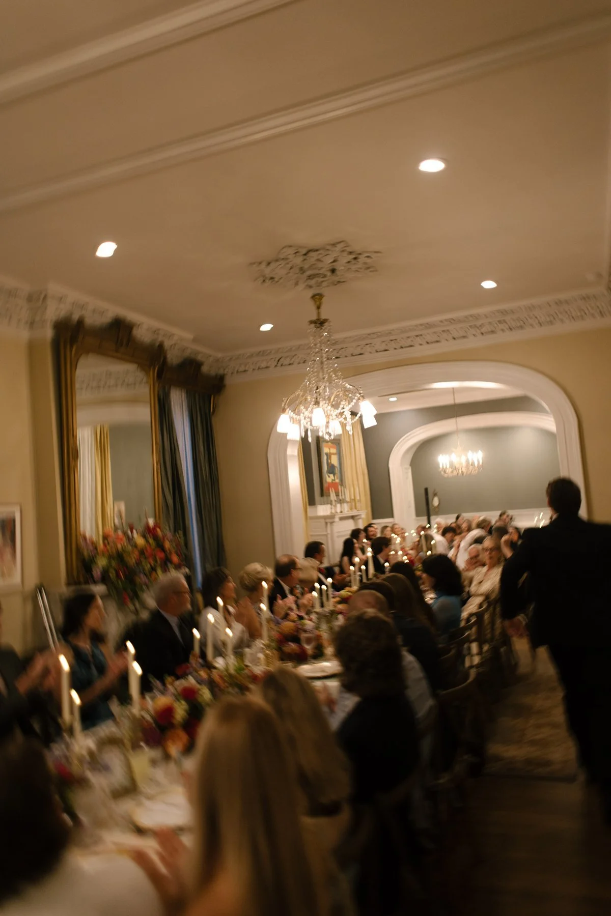 long candlelit reception dinner with guests gathered under chandeliers, warm and lively atmosphere inside a memphis wedding venue