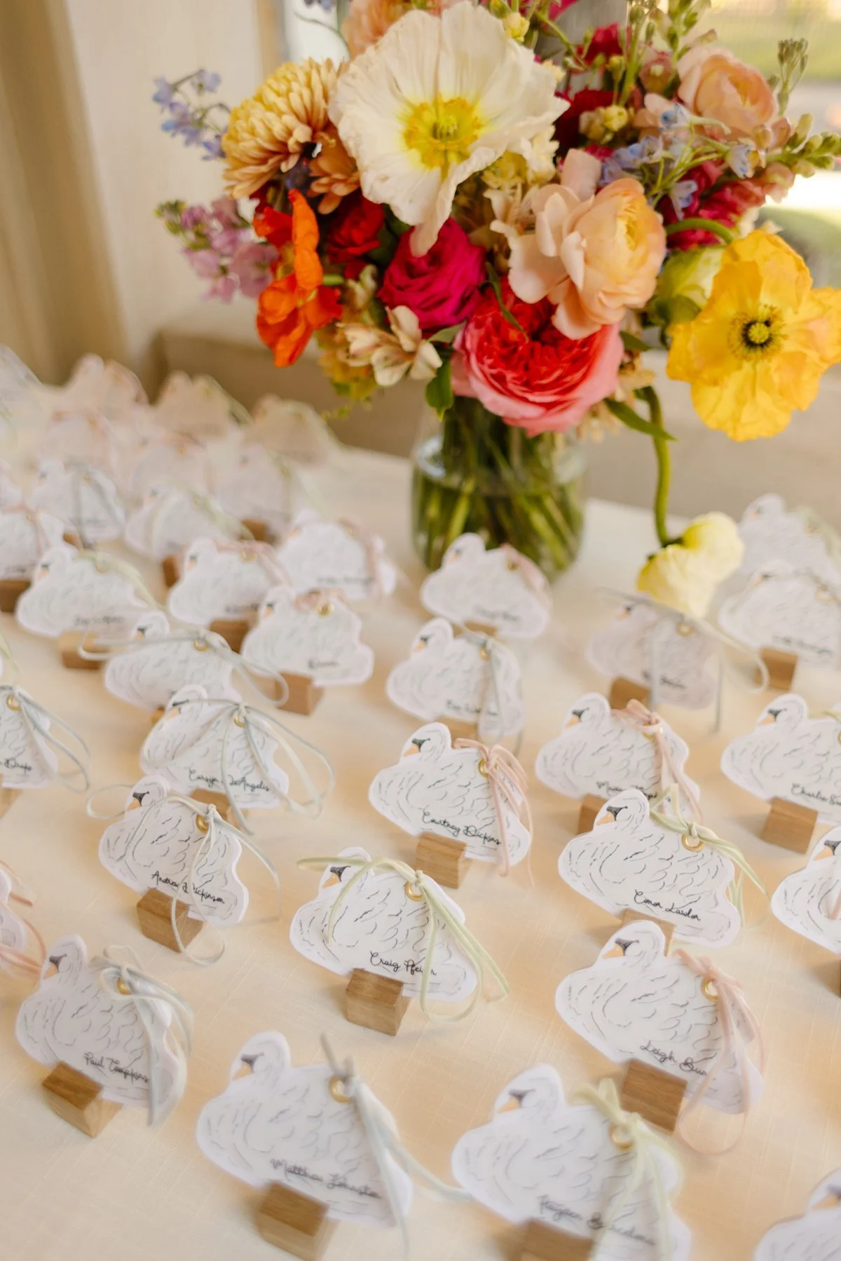 swan-shaped escort cards displayed with colorful florals, whimsical and personalized wedding detail at memphis wedding reception