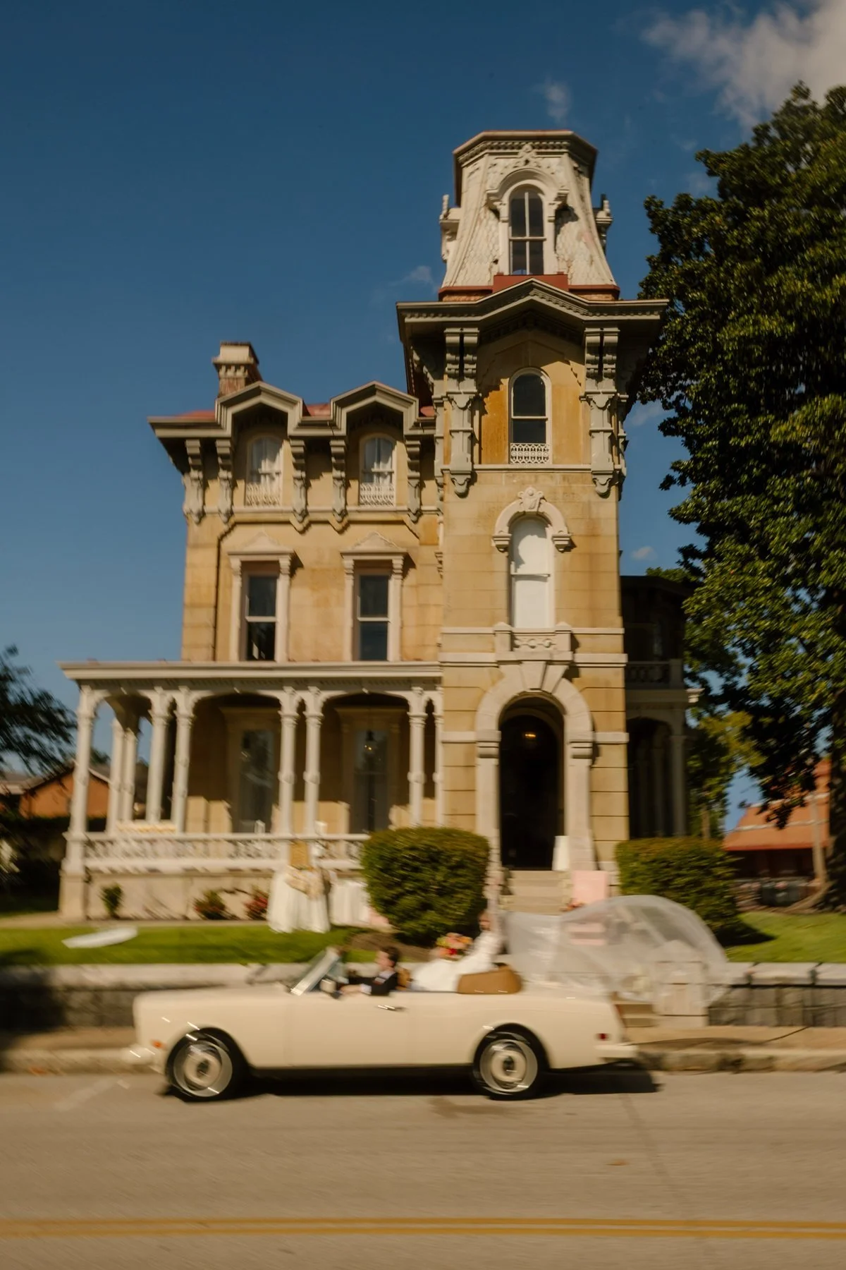 wide shot of historic victorian home with newlyweds in vintage car out front, timeless southern wedding setting