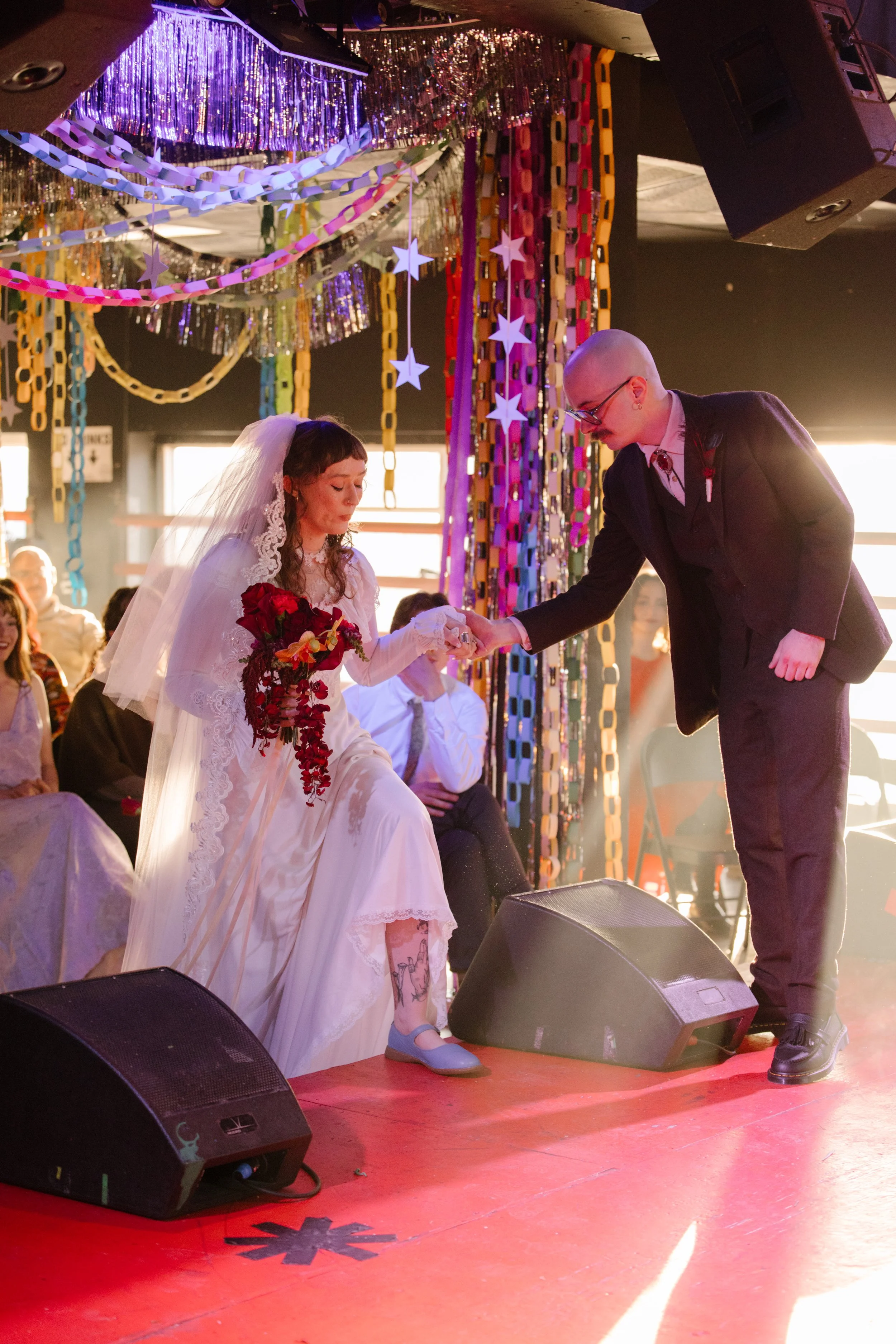 Bride stepping onto a stage with groom’s help during a ceremony surrounded by paper chains and decor inspired by unique wedding ideas