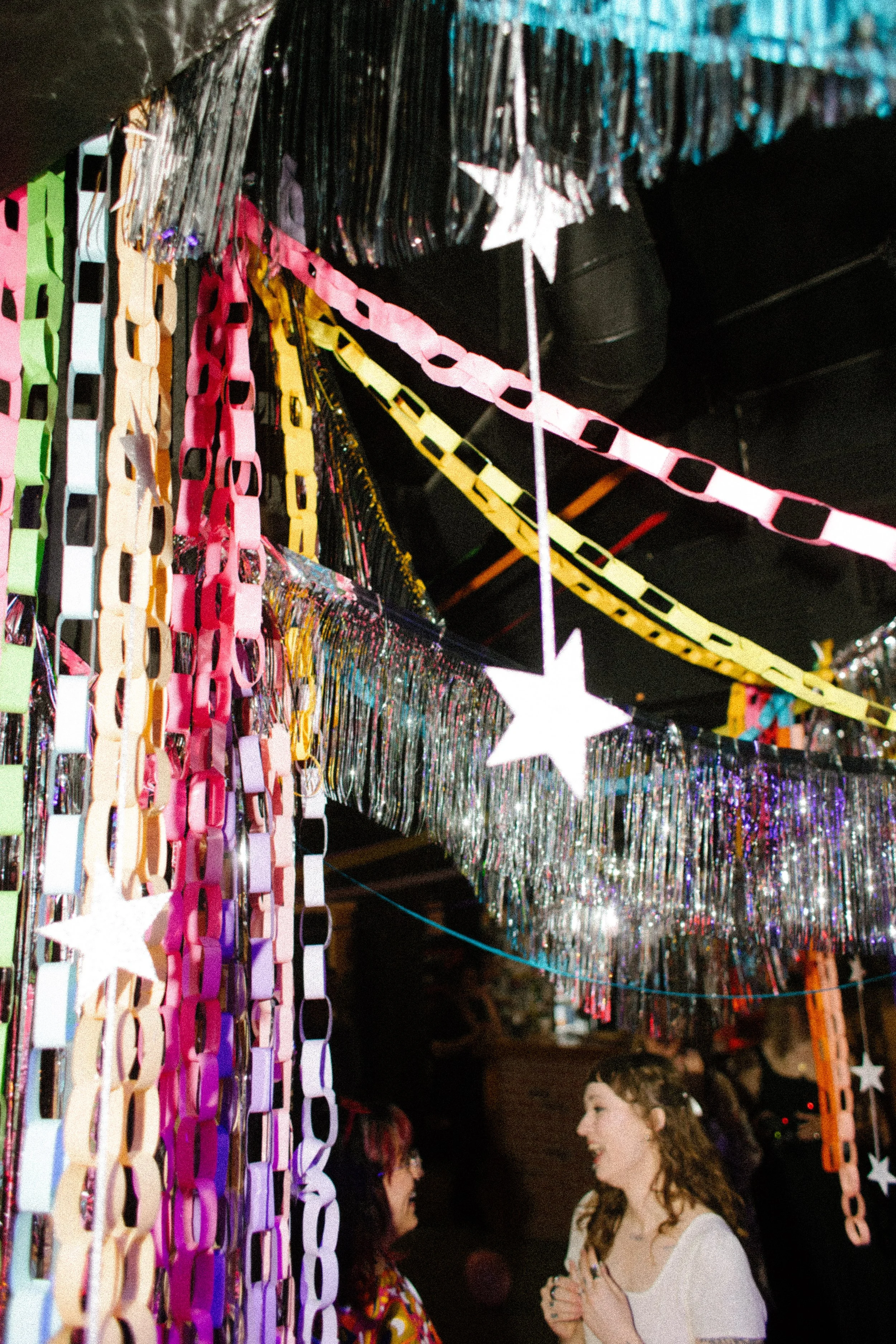 Colorful paper chains and tinsel decorations hanging from the ceiling as part of creative and handmade unique wedding ideas