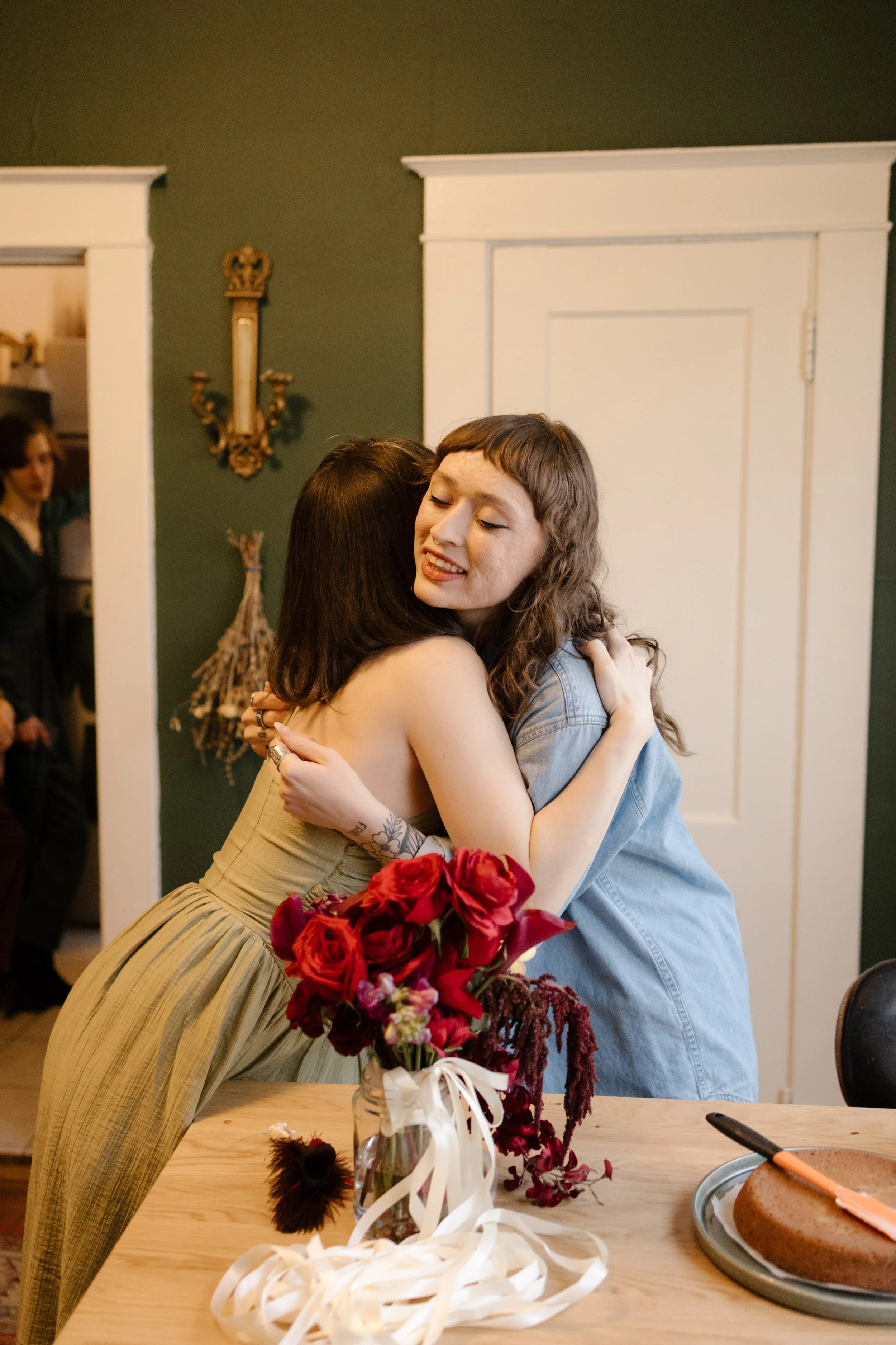 Bride hugging a friend in a cozy kitchen during wedding morning, capturing emotional and intimate getting ready moments