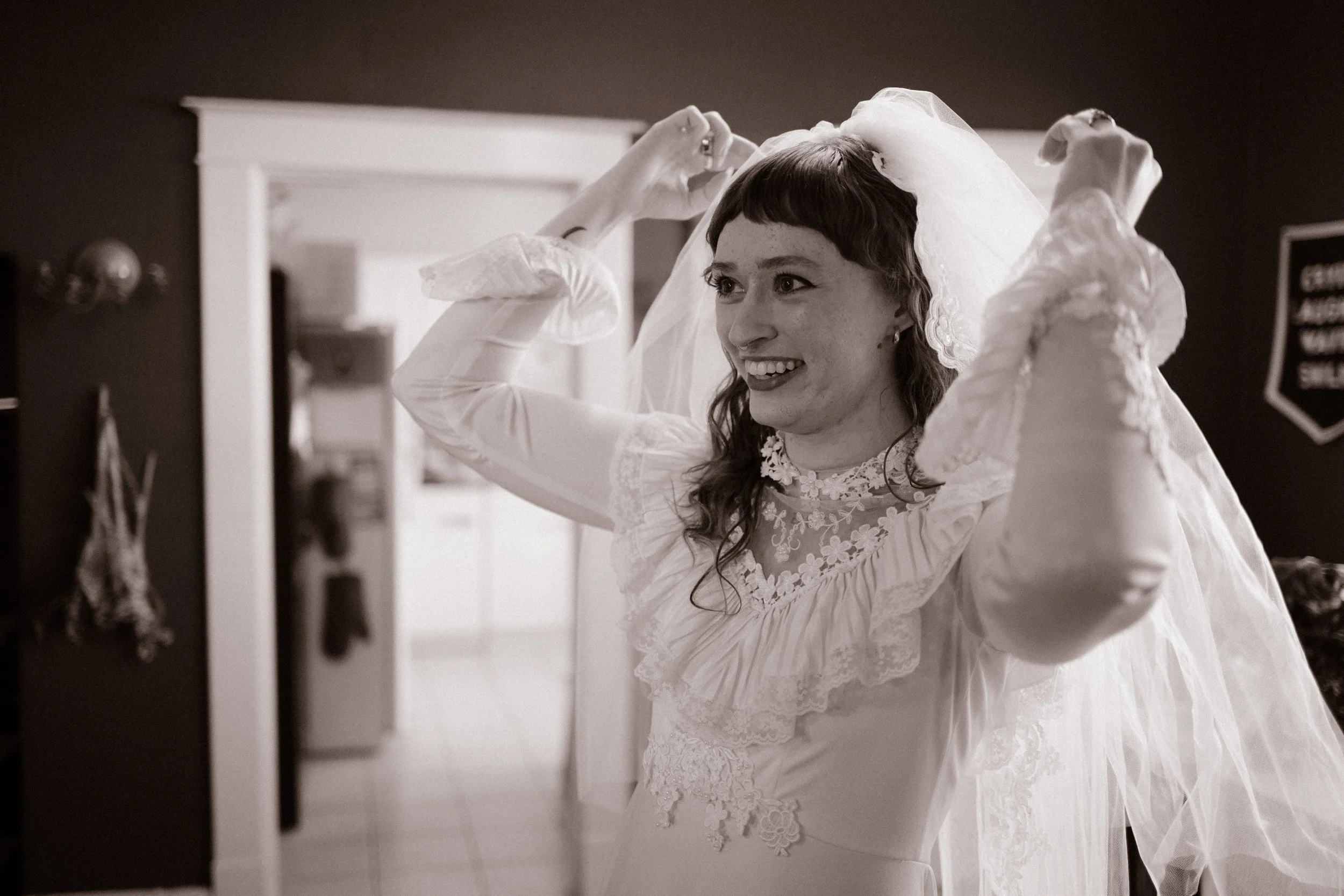 Black and white photo of bride adjusting her veil, capturing timeless and emotional getting ready moments