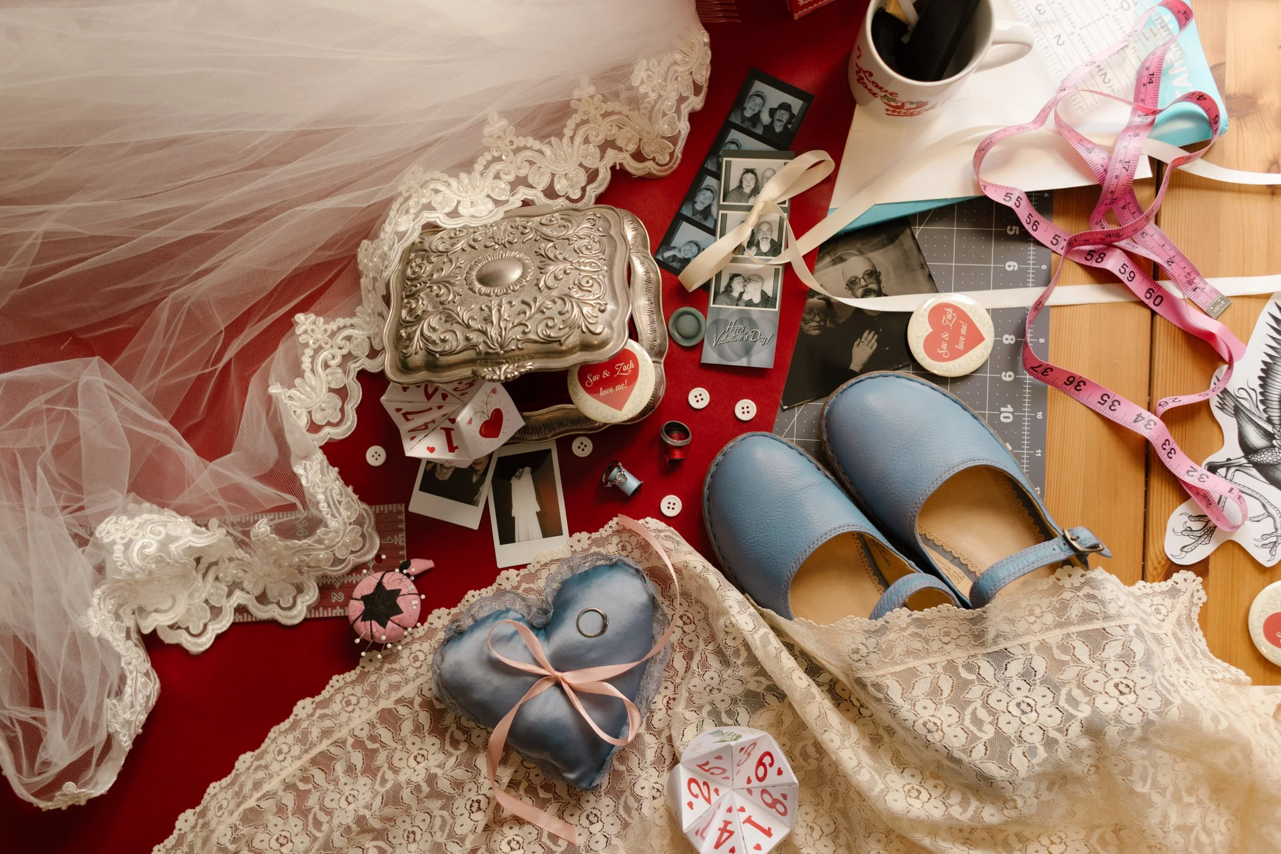 Flat lay of wedding details including lace veil, vintage box, blue shoes, film strips, and personal keepsakes reflecting unique wedding ideas and storytelling elements