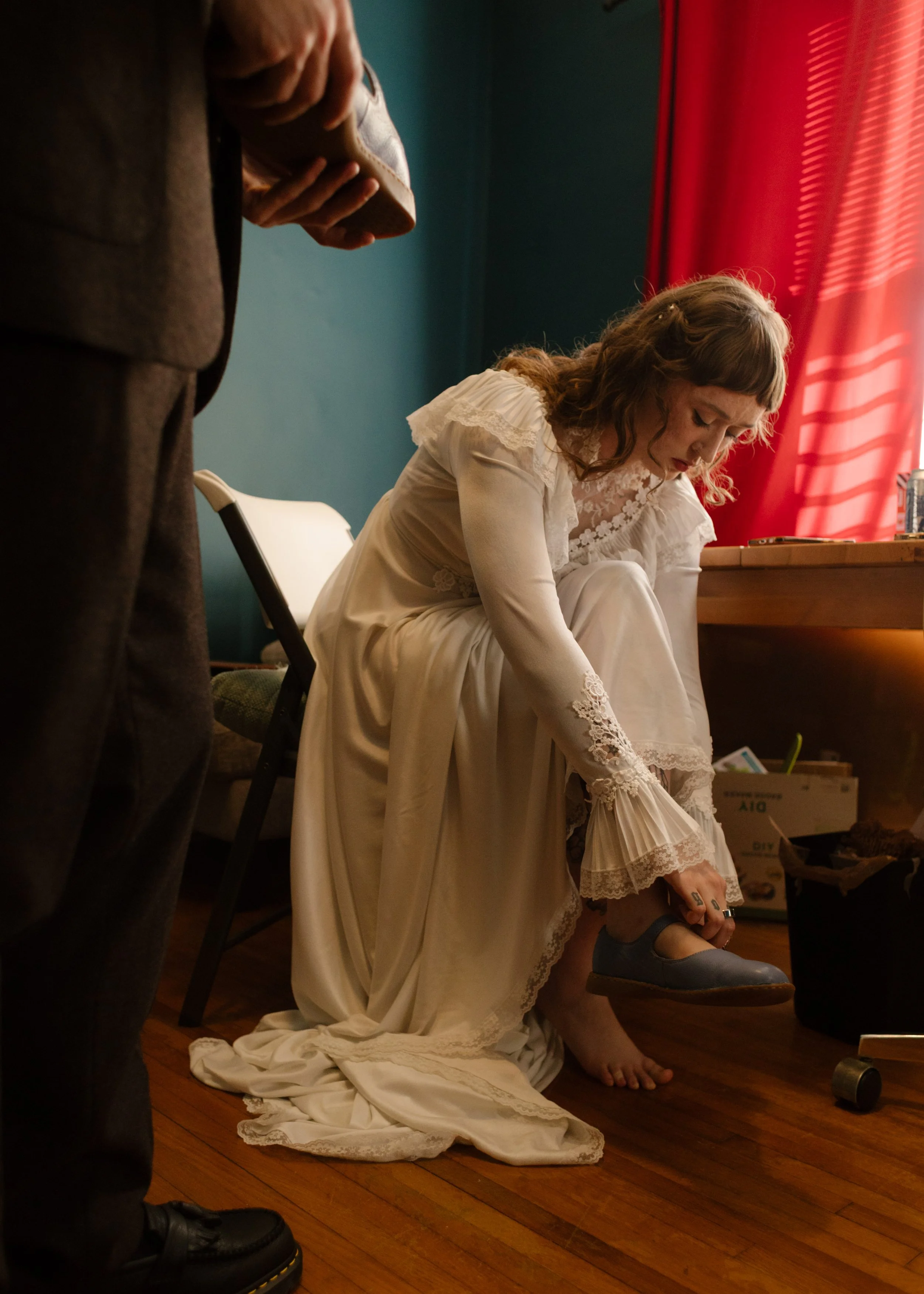 Bride putting on blue shoes in a softly lit room, reflecting candid and intentional unique wedding ideas during getting ready