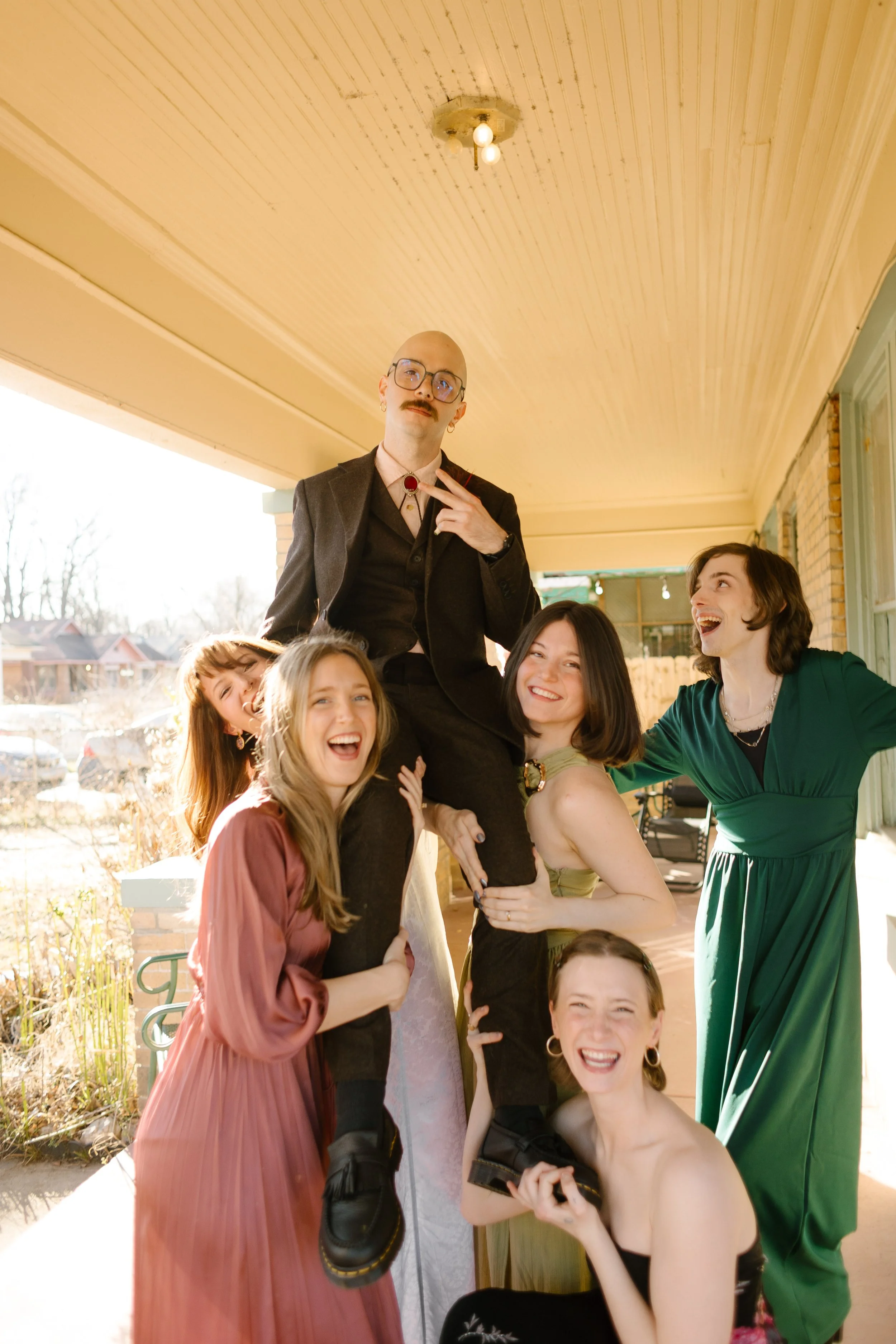 Groom being lifted by friends on a porch during wedding morning, capturing playful and personality-filled unique wedding ideas