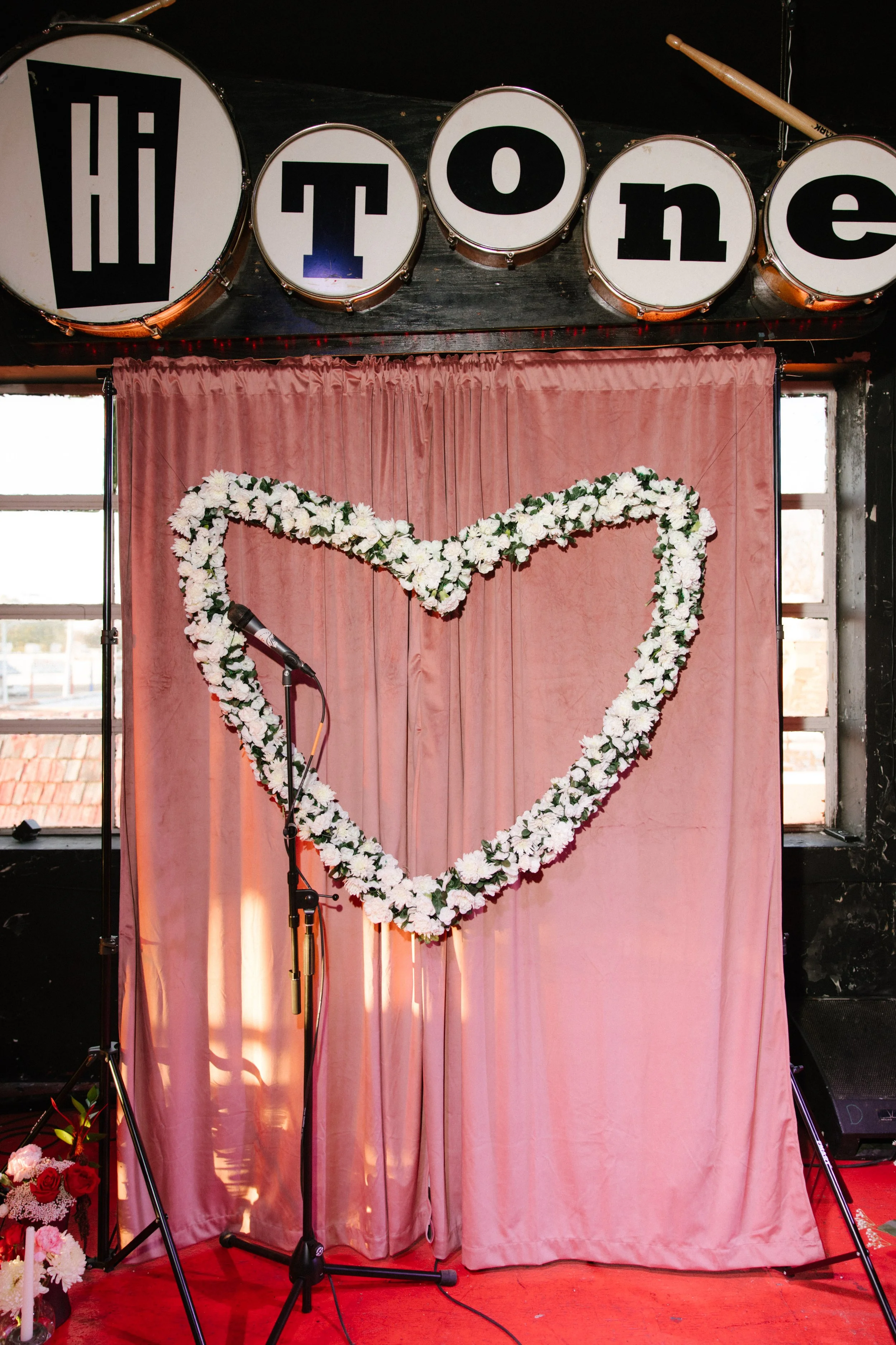 Ceremony backdrop with heart-shaped florals and stage setup at The Hi Tone in Memphis, reflecting creative and non-traditional unique wedding ideas