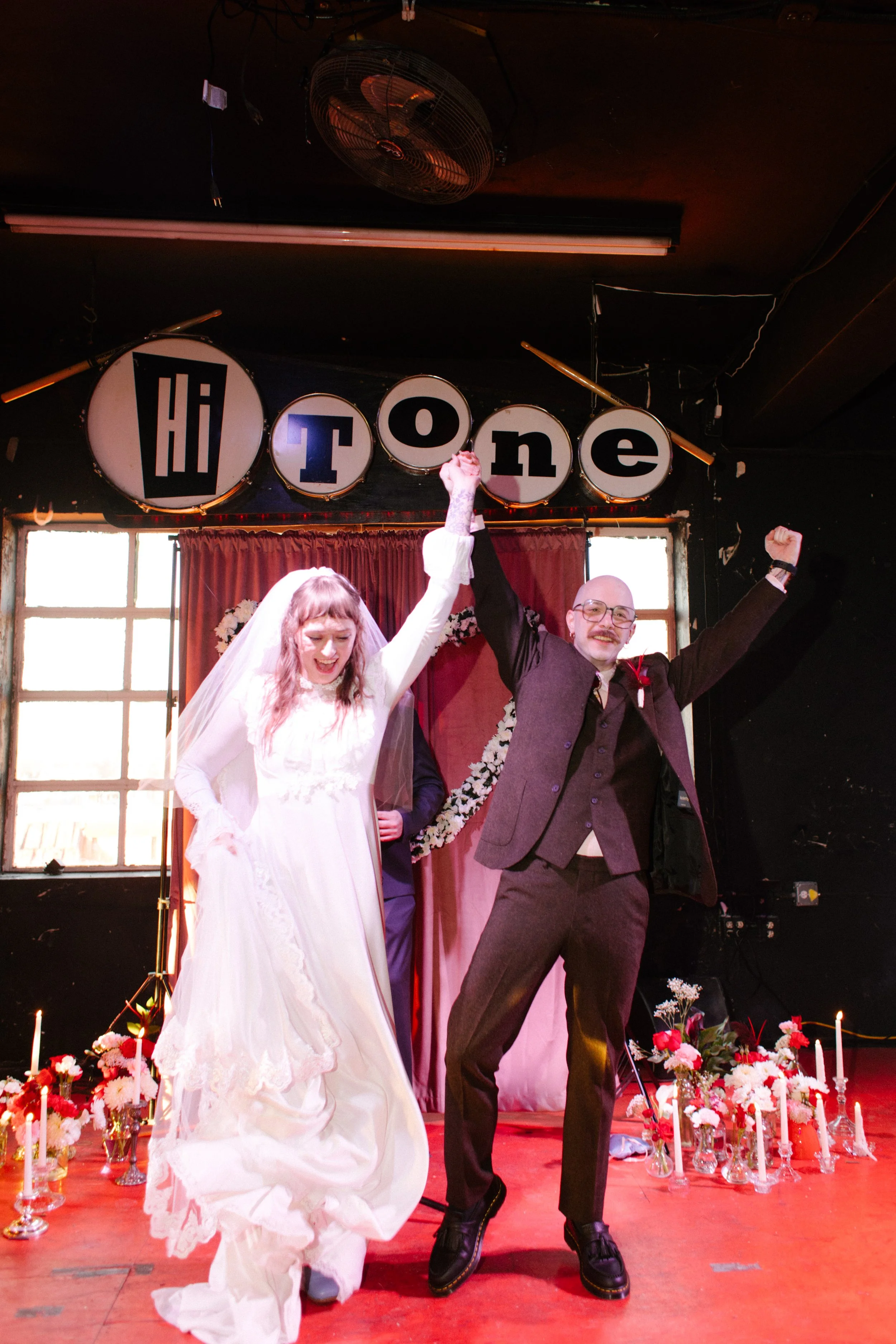 Bride and groom celebrating after ceremony on stage with raised hands, reflecting joyful and unconventional unique wedding ideas