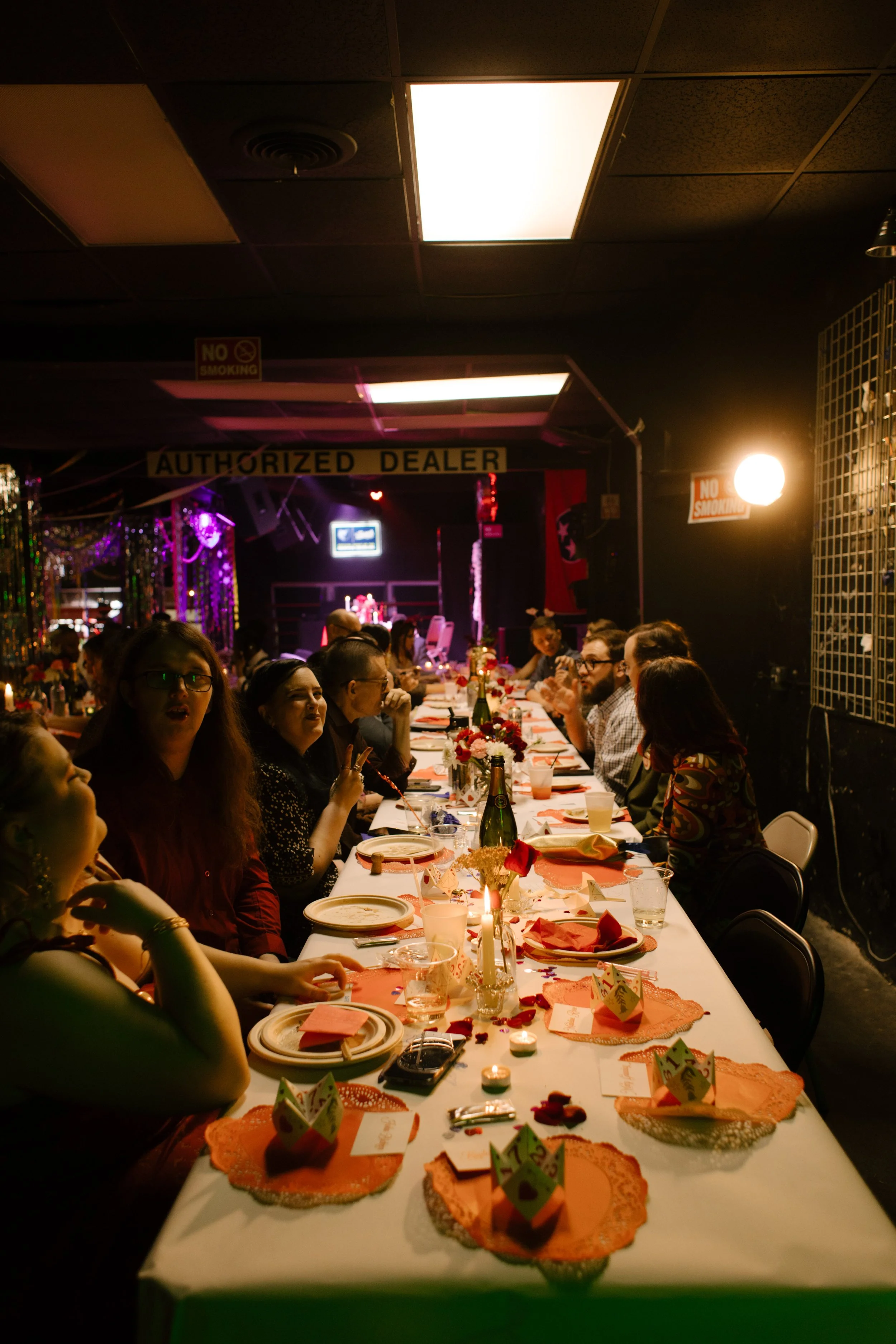 Guests seated at long reception table with candles and red details, capturing intimate and community-focused wedding dinner