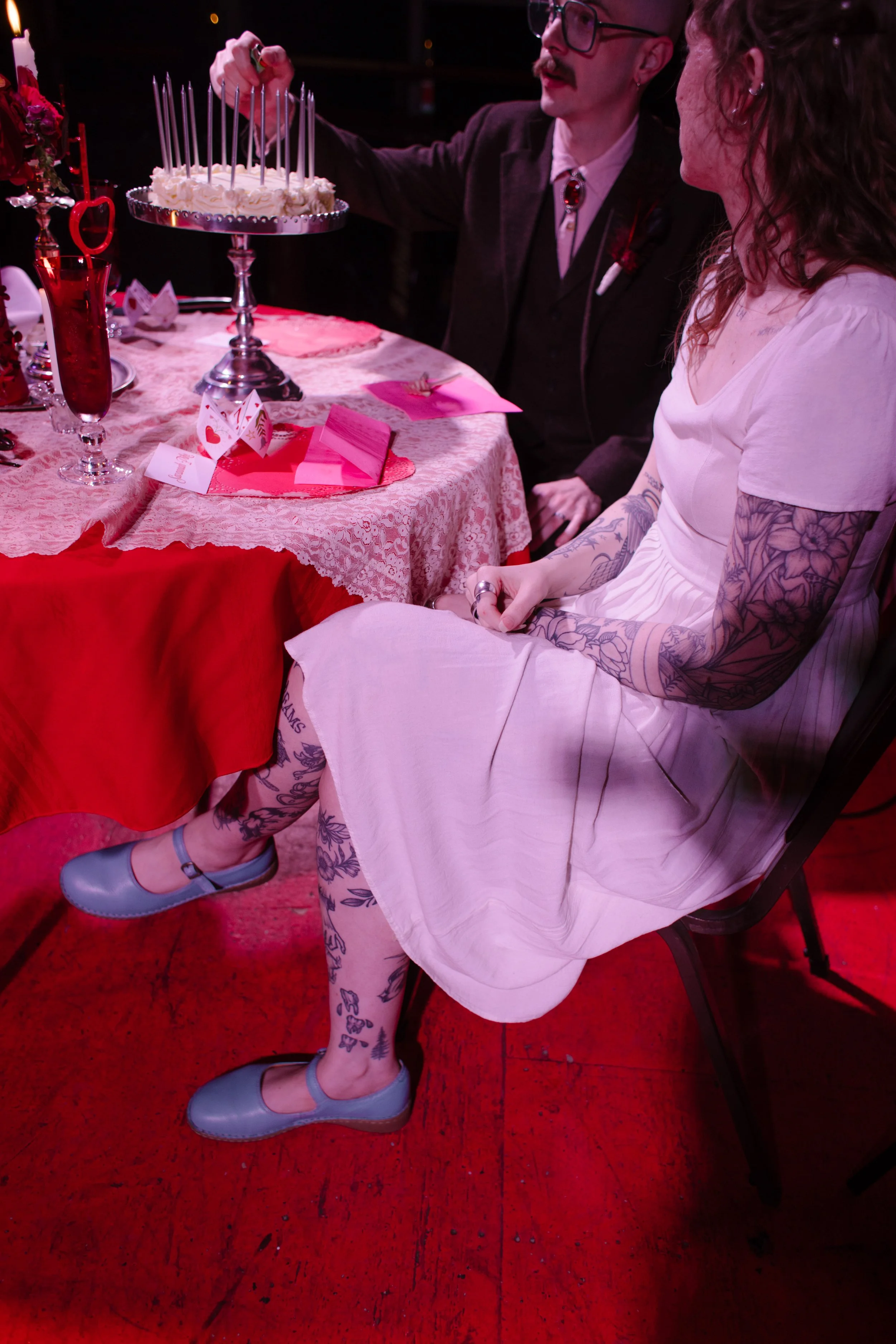 Bride and groom sitting at table while lighting candles on a wedding cake, showcasing interactive and meaningful unique wedding ideas