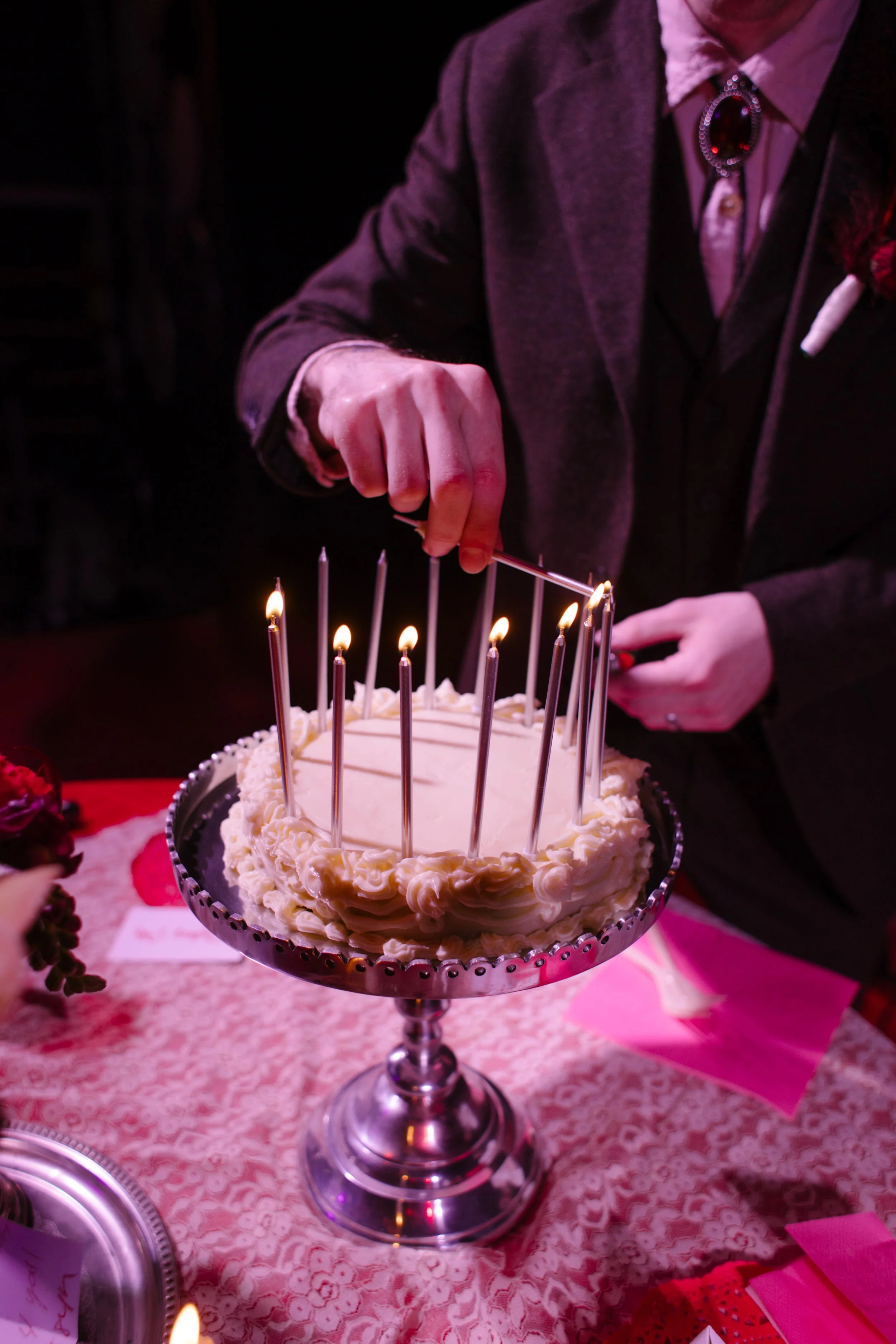 Close-up of wedding cake with tall candles being lit, highlighting vintage-inspired and creative unique wedding ideas
