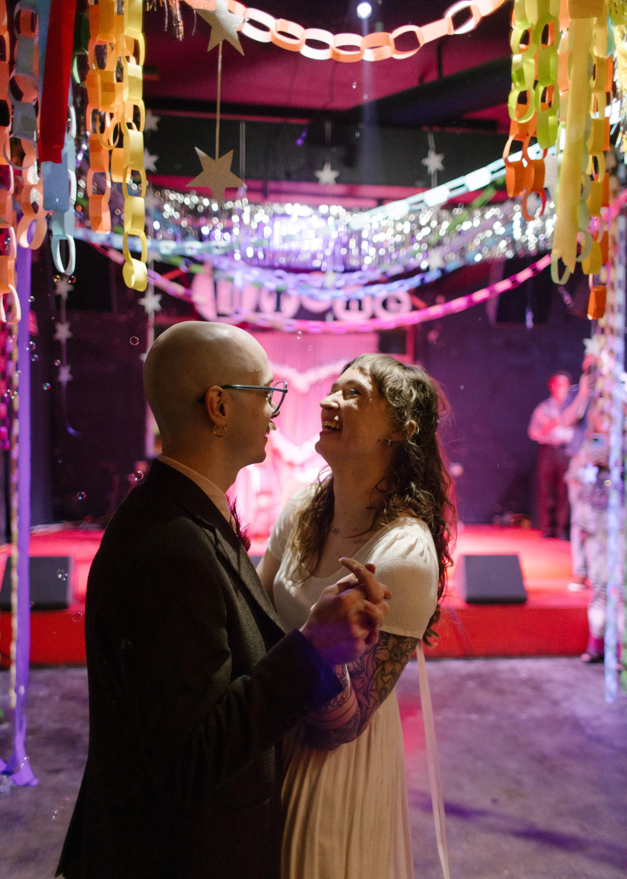 Couple dancing together under colorful paper chains and lights at a reception, capturing playful and expressive unique wedding ideas