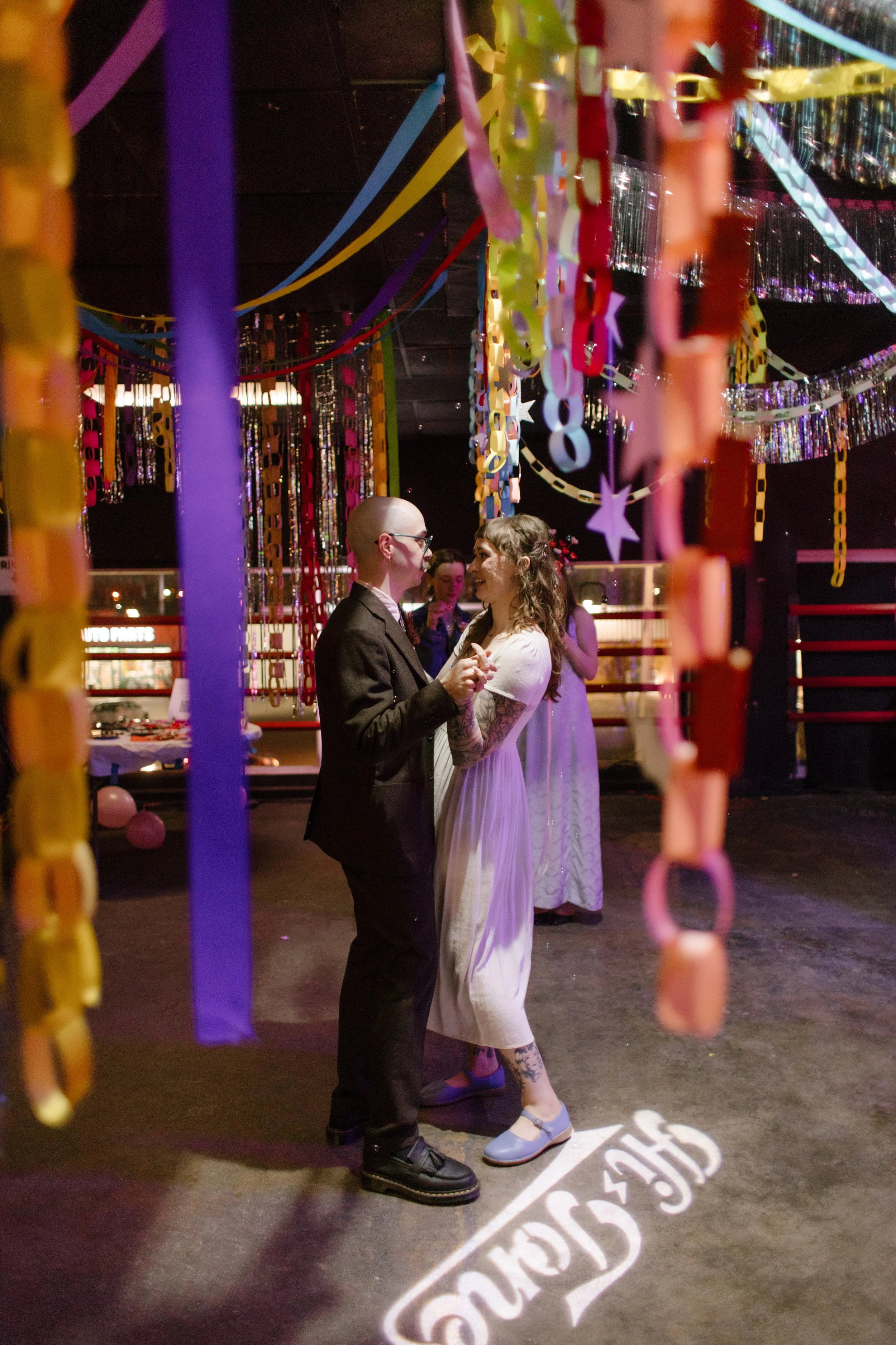 Couple slow dancing under vibrant paper chains and streamers, showcasing bold and immersive unique wedding ideas