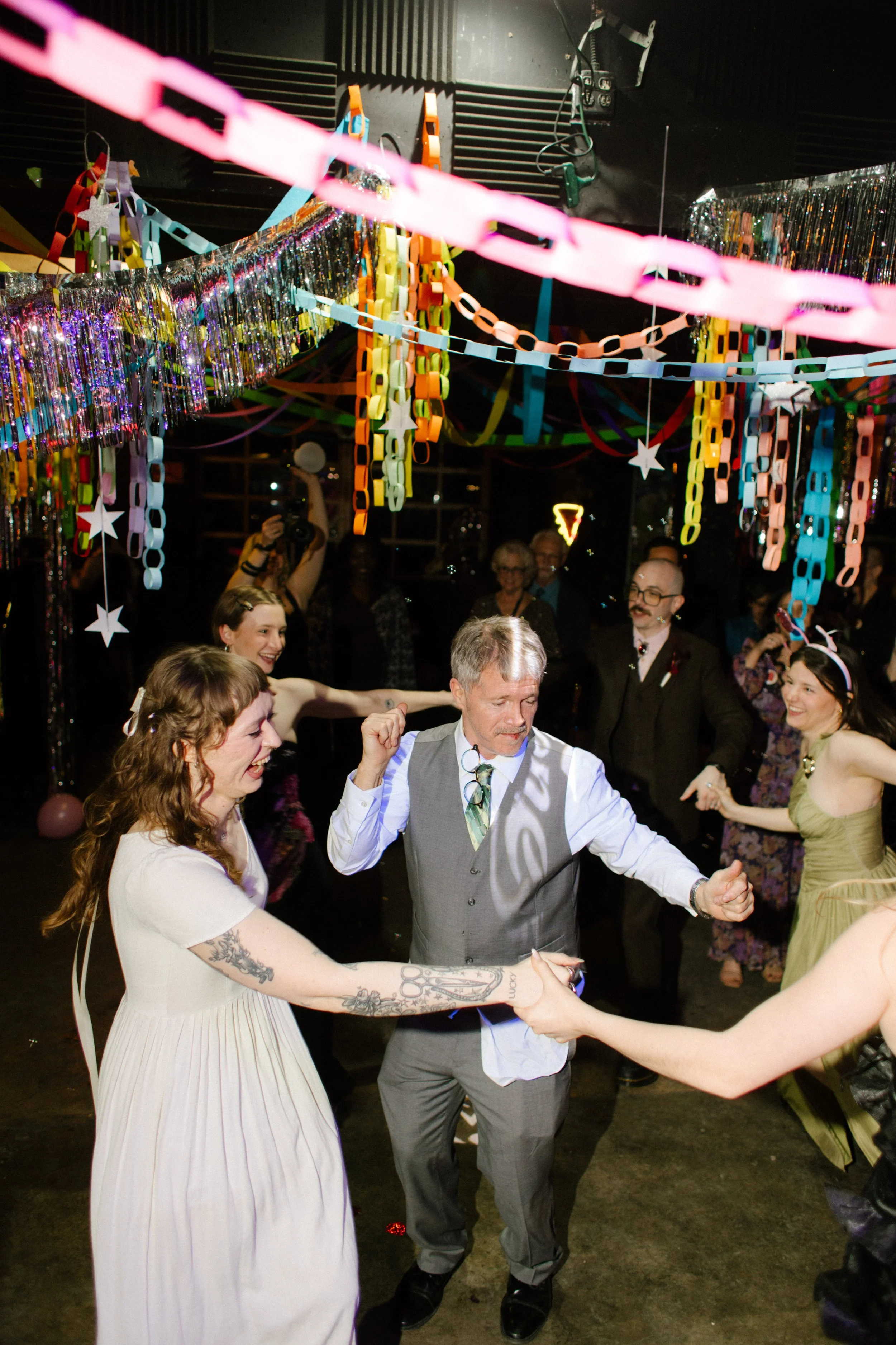 Guests dancing together under colorful paper chains and hanging decor, highlighting fun and interactive unique wedding ideas