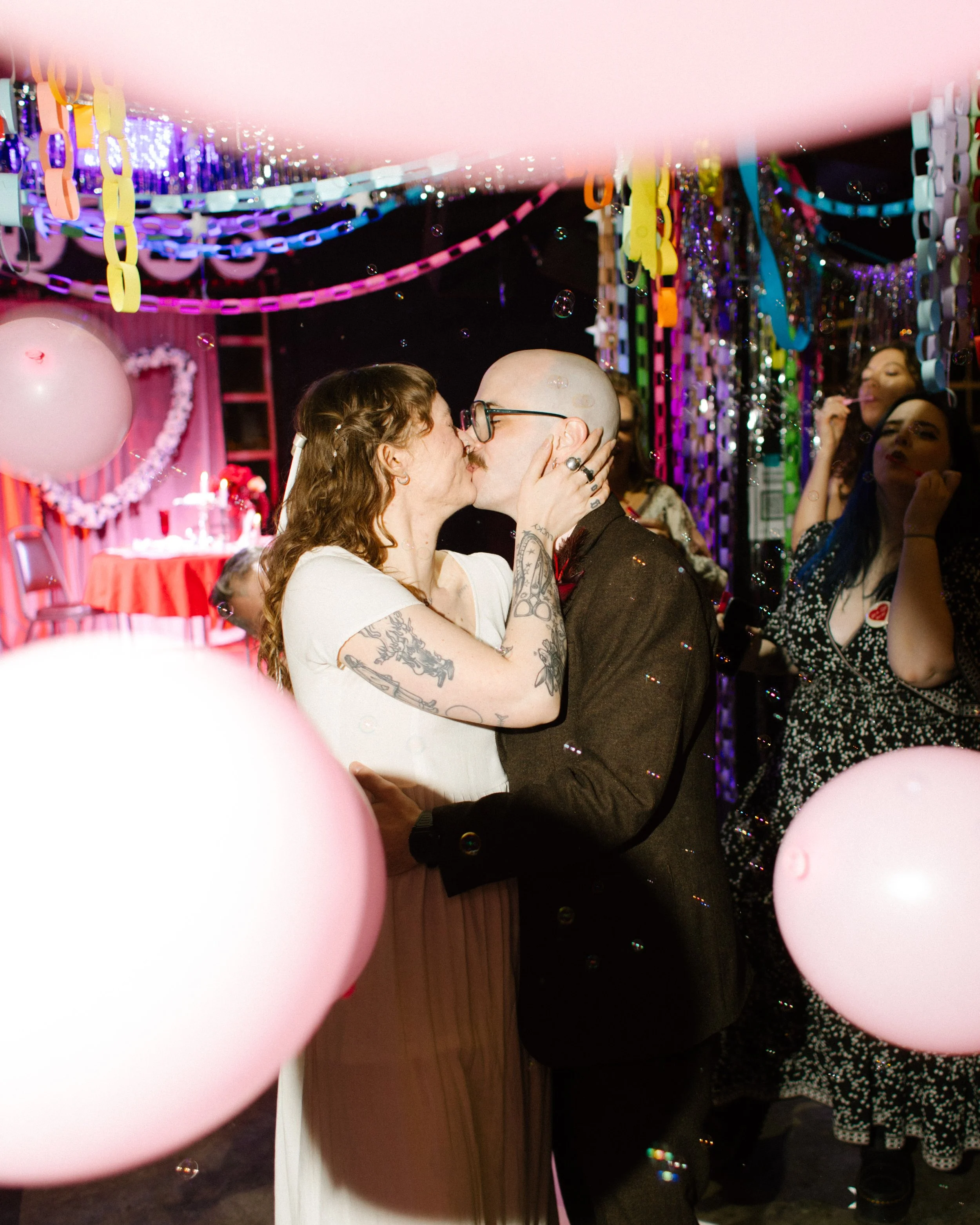 Bride and groom kissing during reception surrounded by balloons and bubbles, capturing playful and candid unique wedding ideas