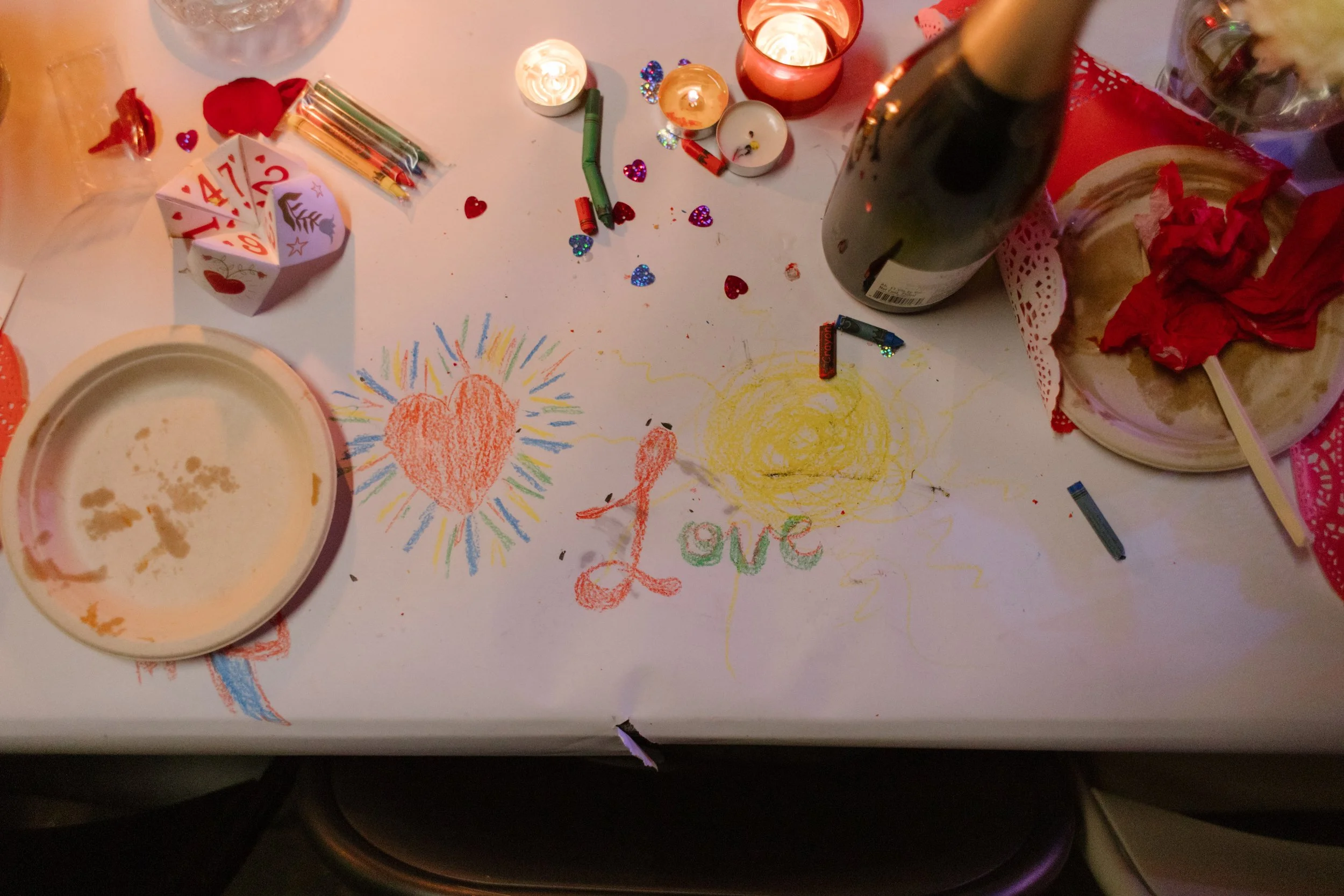 Reception table covered in crayon drawings, candles, and playful details, showcasing interactive and artistic unique wedding ideas