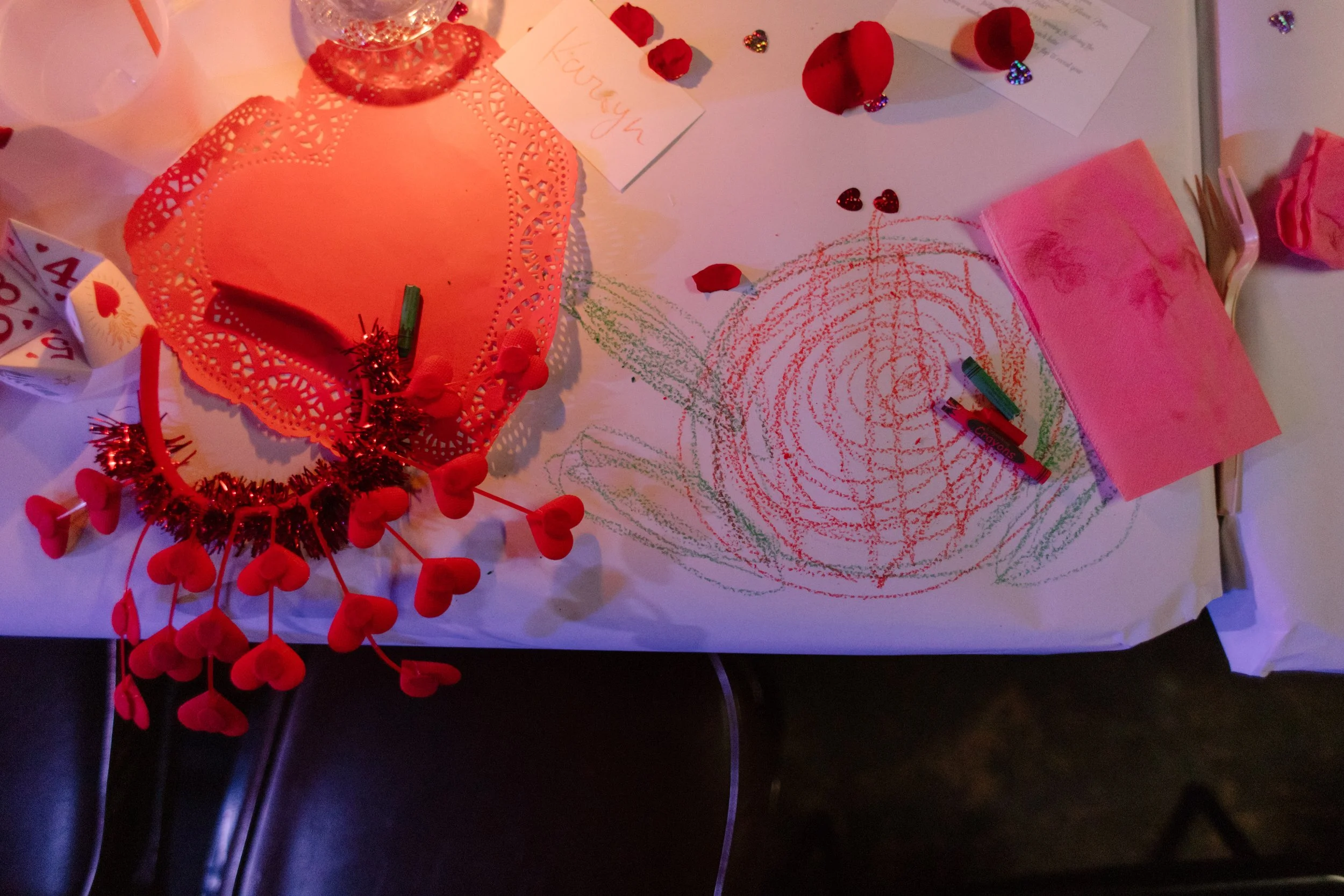 Reception table with crayon drawings, rose petals, and playful decor details, highlighting interactive and creative unique wedding ideas