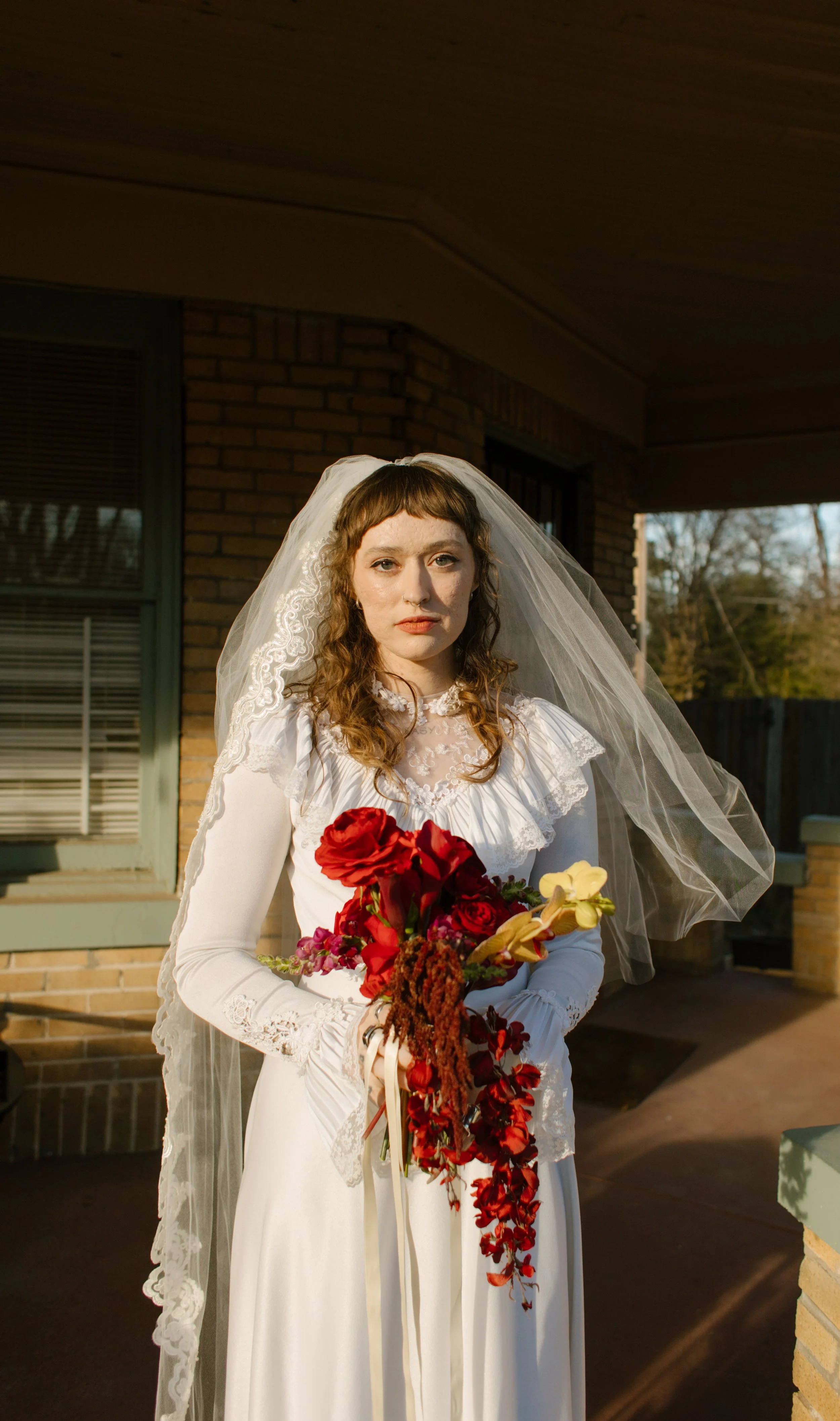 Bride holding red bouquet during golden hour portraits, capturing romantic and modern unique wedding ideas