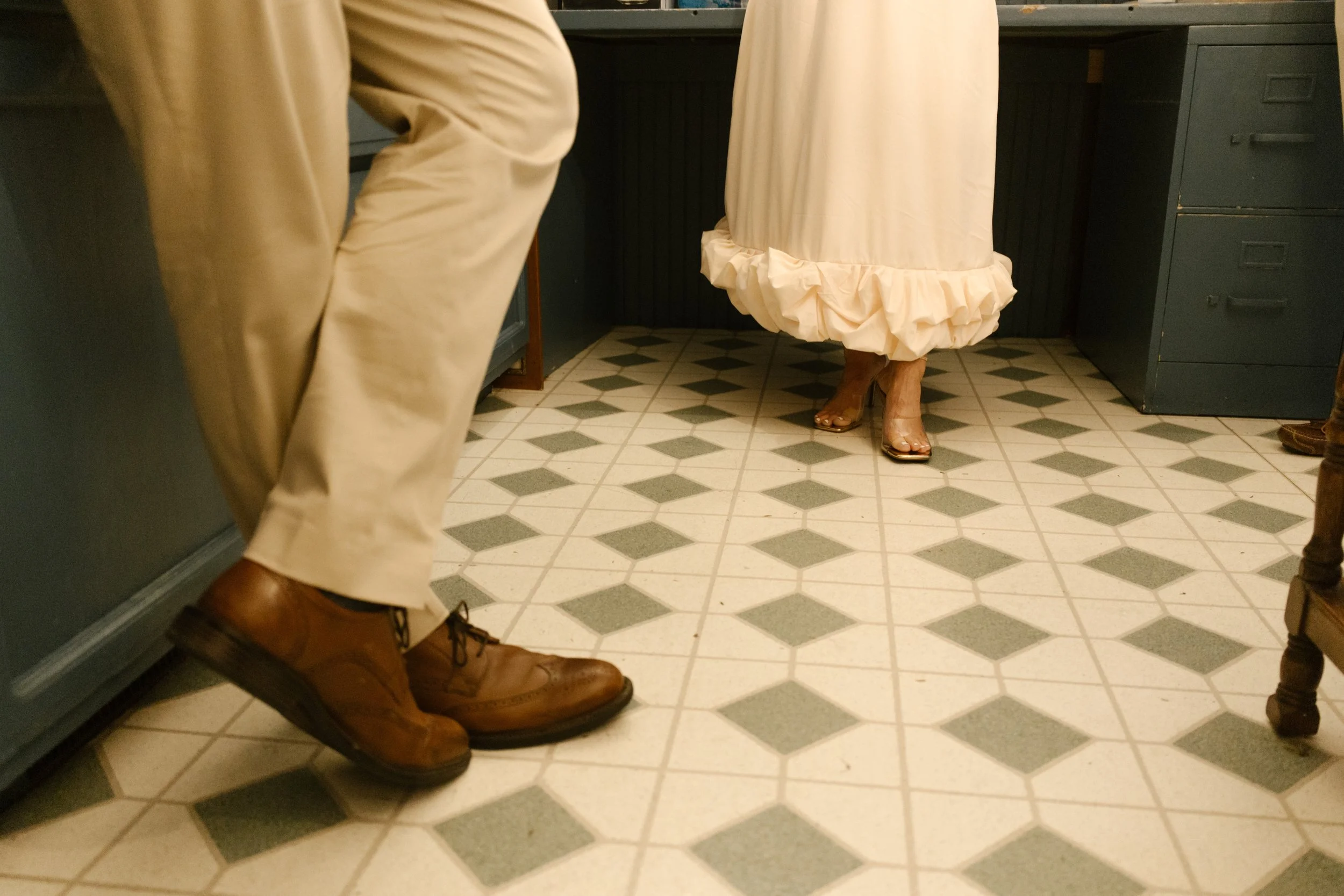 Candid detail of guests’ shoes and movement on patterned tile flooring during a wedding celebration