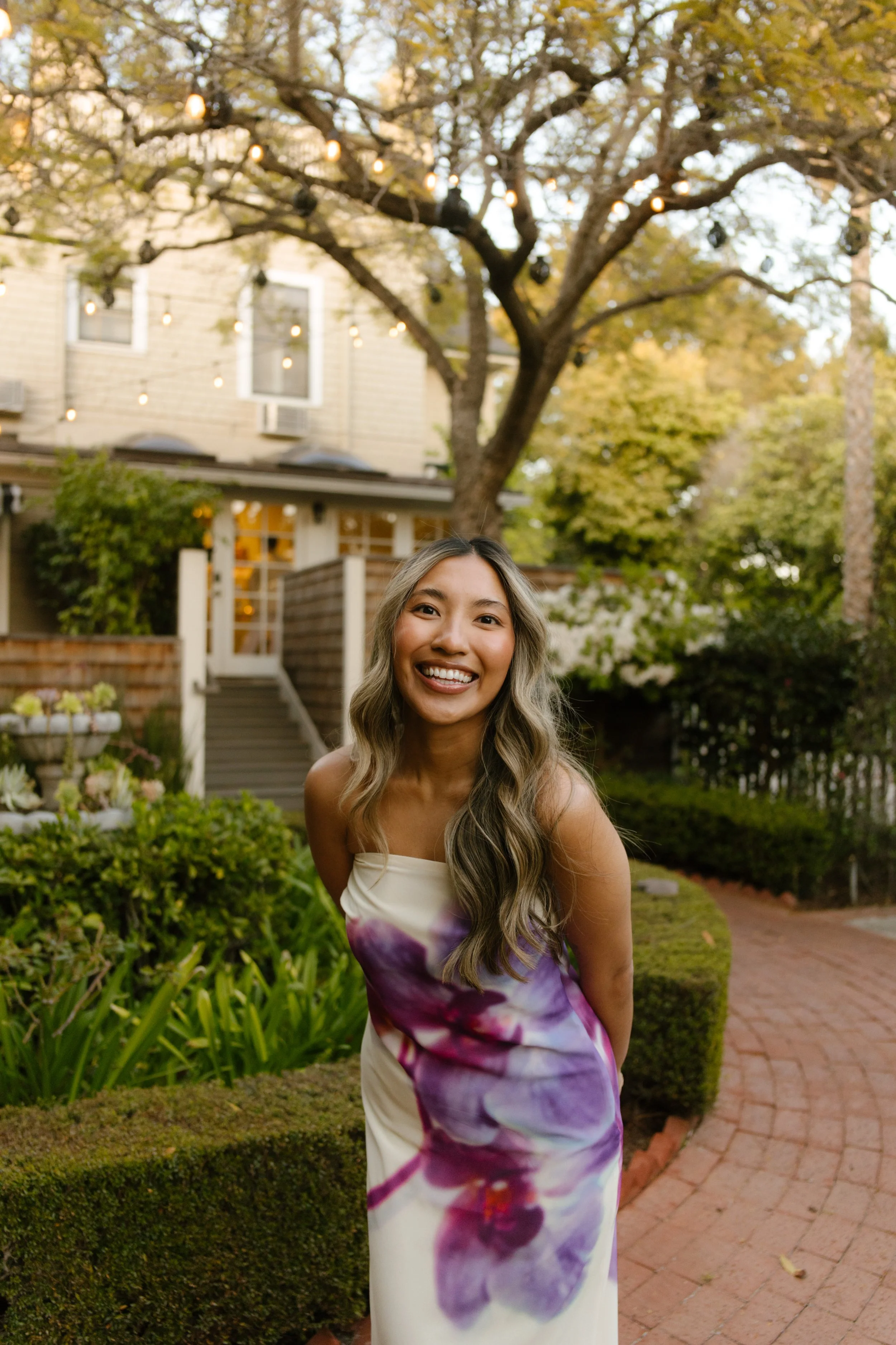 Bride smiling in a garden with a coastal home behind her during a wedding in Santa Barbara