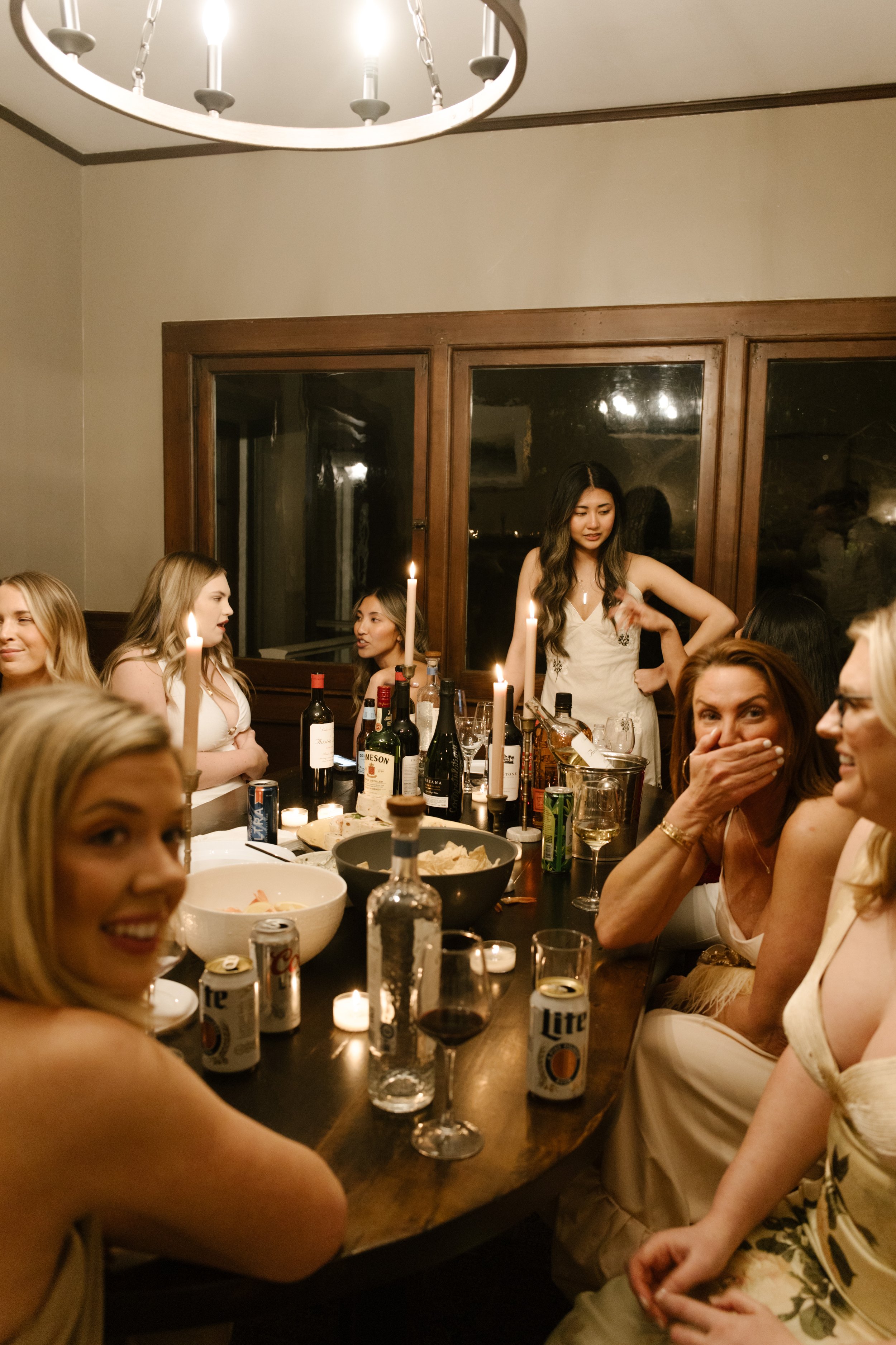 Guests gathered around a candlelit dinner table sharing stories and laughter during an intimate wedding evening