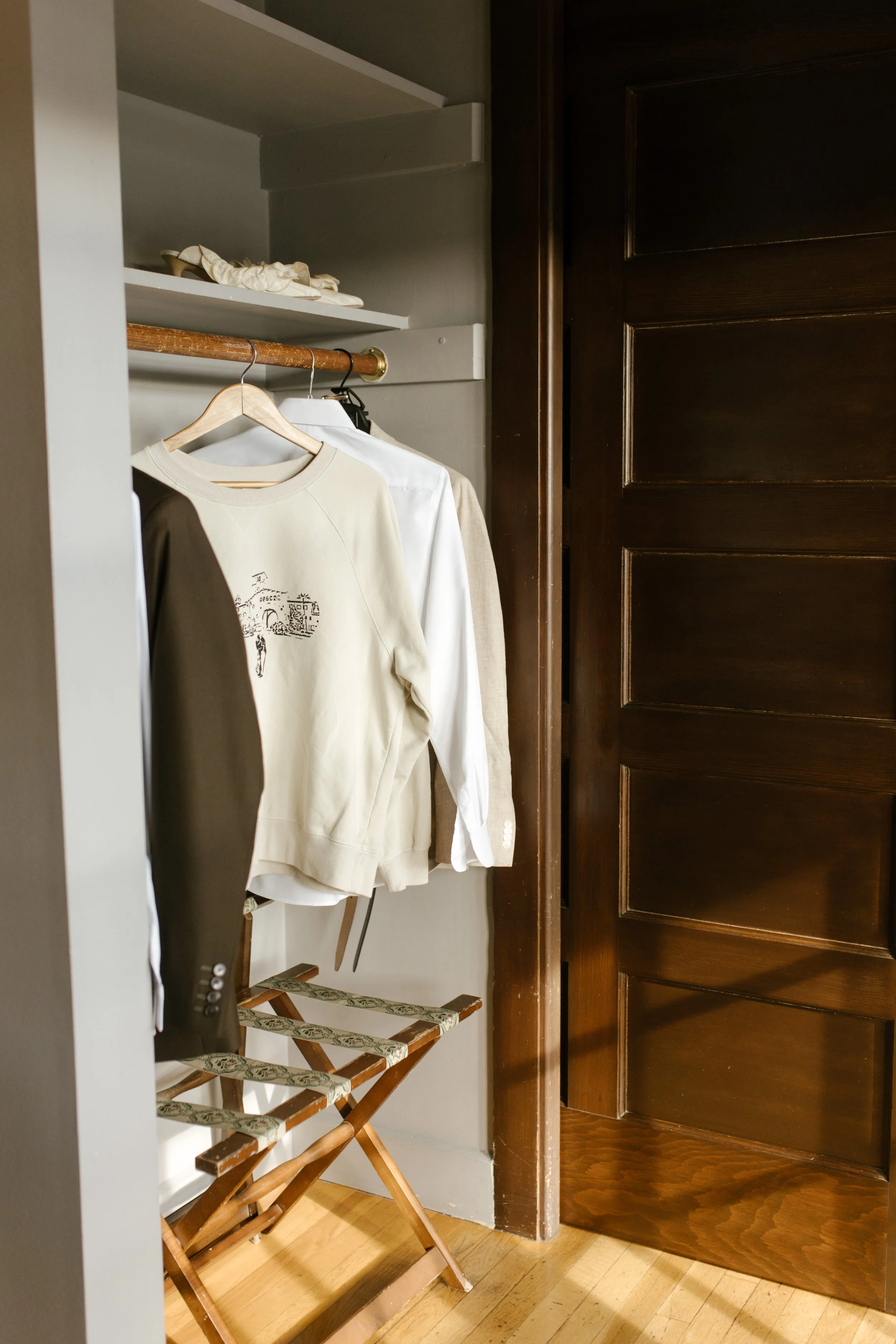 Bride and groom getting ready details with neutral outfits hanging in a sunlit room during a wedding in Santa Barbara