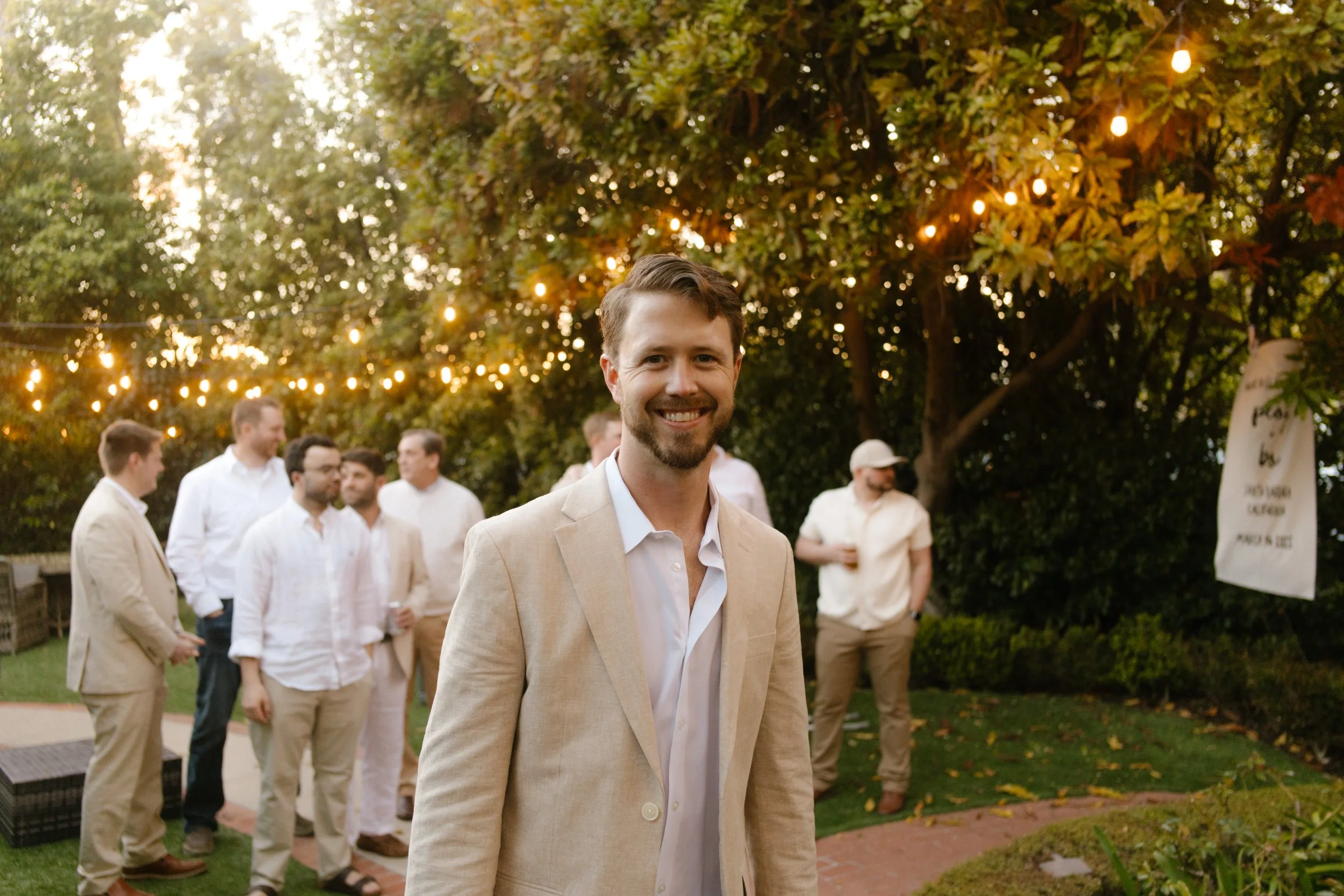 Groom portrait outdoors under string lights during a wedding in Santa Barbara