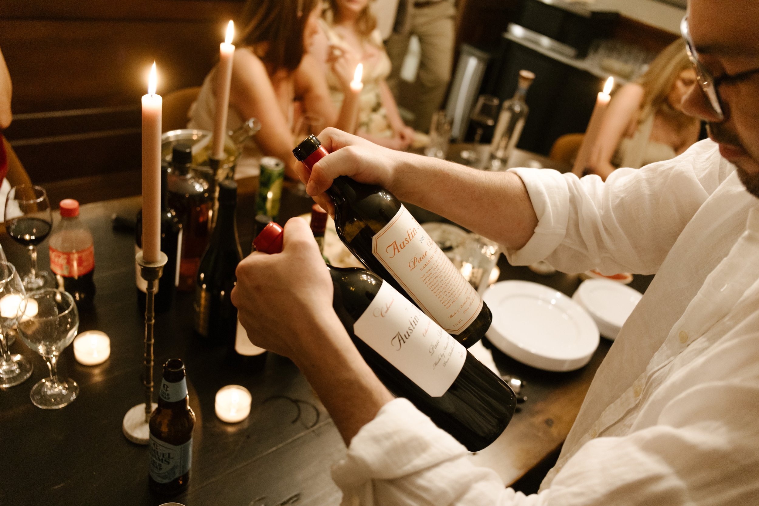 Close-up of wine being opened over a candlelit dinner table during a wedding reception