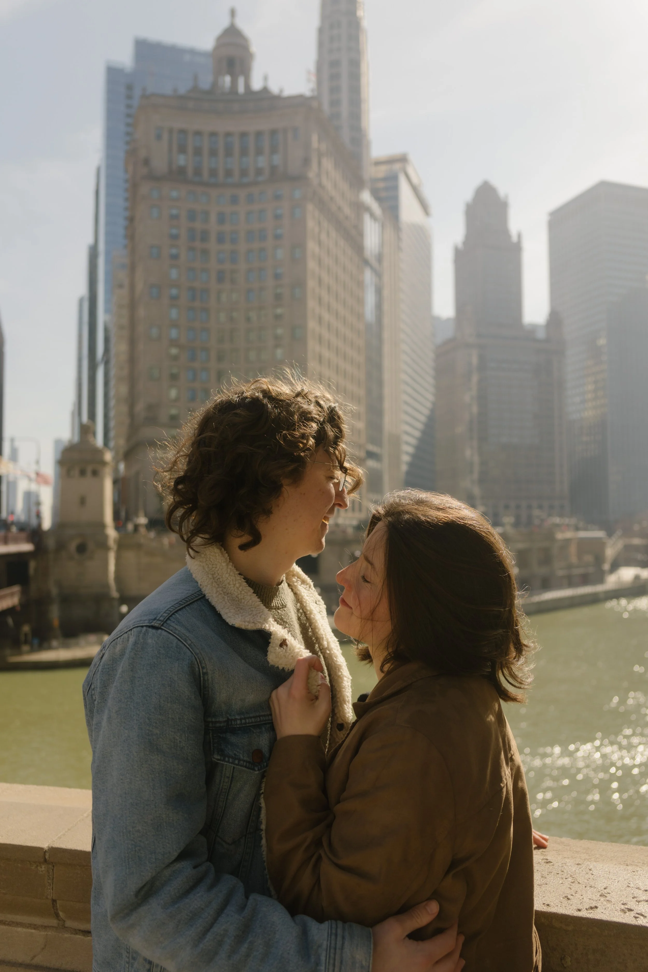 Intimate close-up of couple holding each other along the river with historic Chicago buildings rising behind them