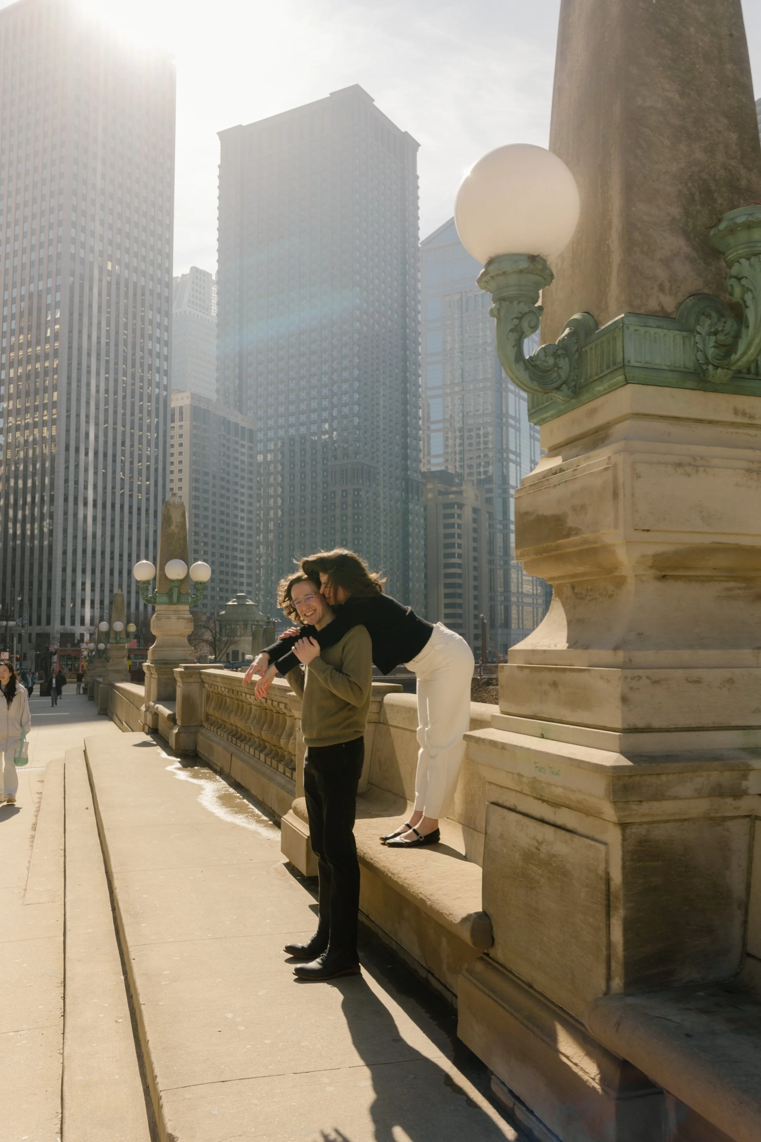 Couple laughing together on a Chicago bridge as one leans over the ledge, capturing a playful moment during engagement photos in Chicago