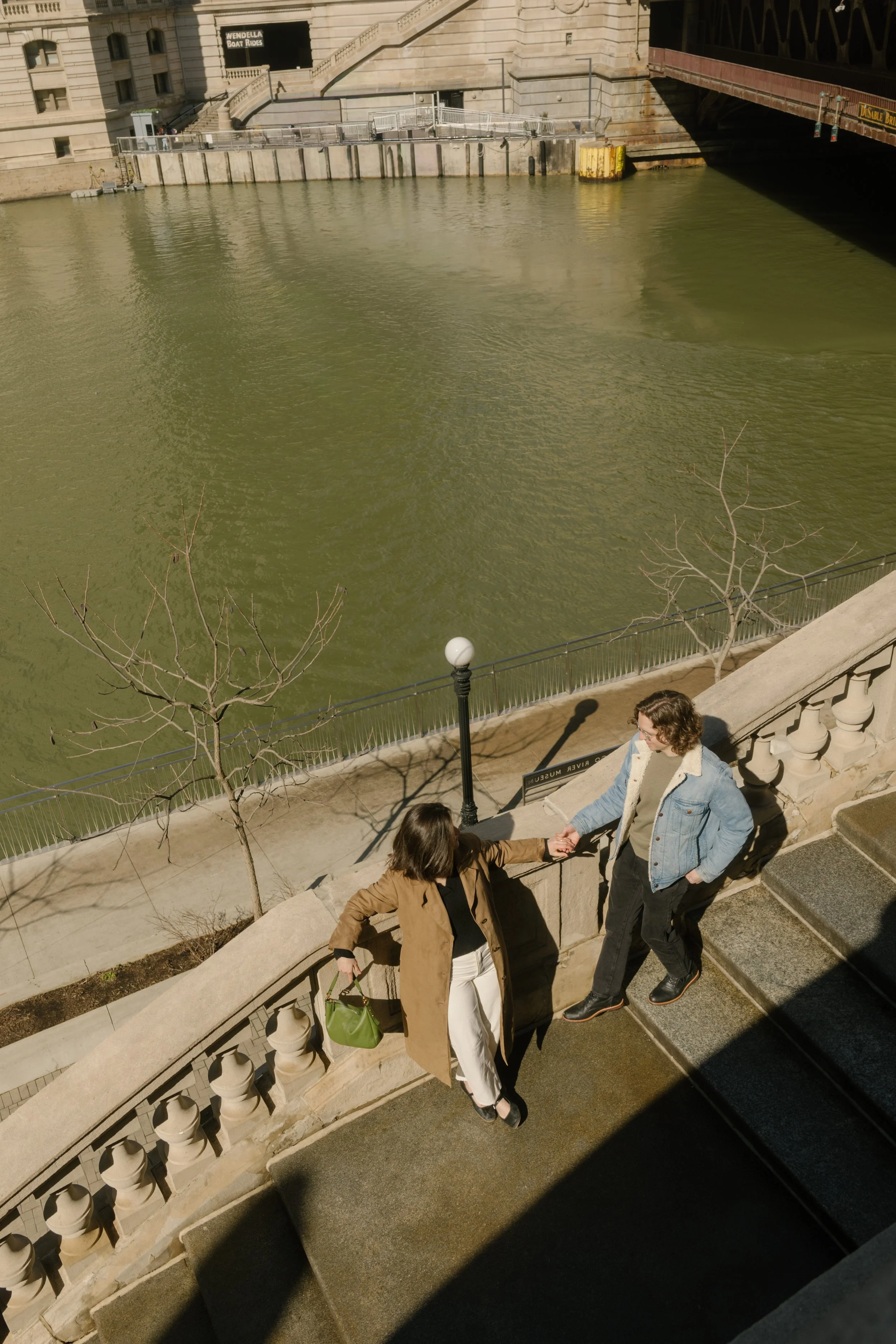 Overhead view of couple holding hands and walking down stone steps near the Chicago River