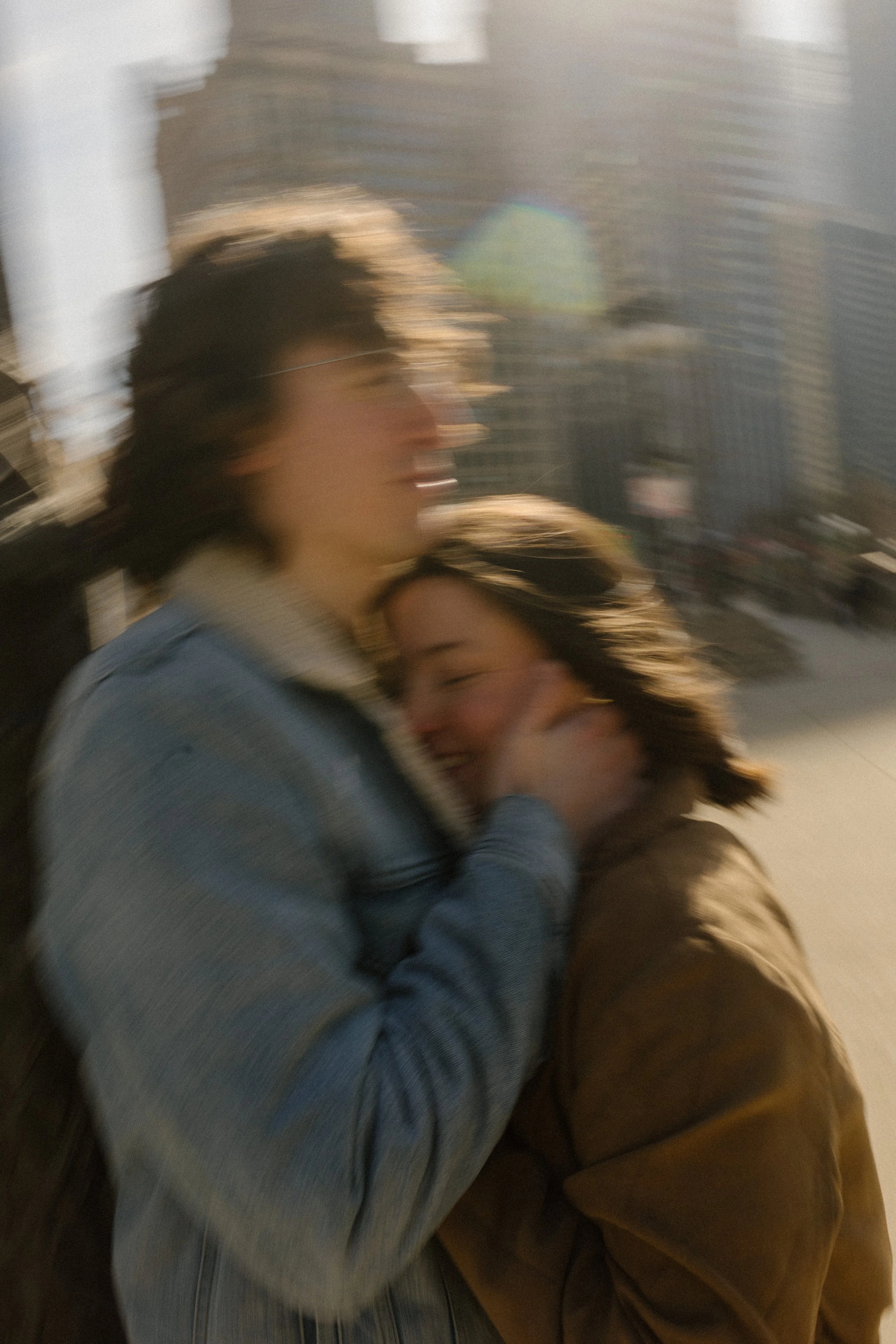Motion blur close-up of couple embracing and laughing with sunlight and city movement around them