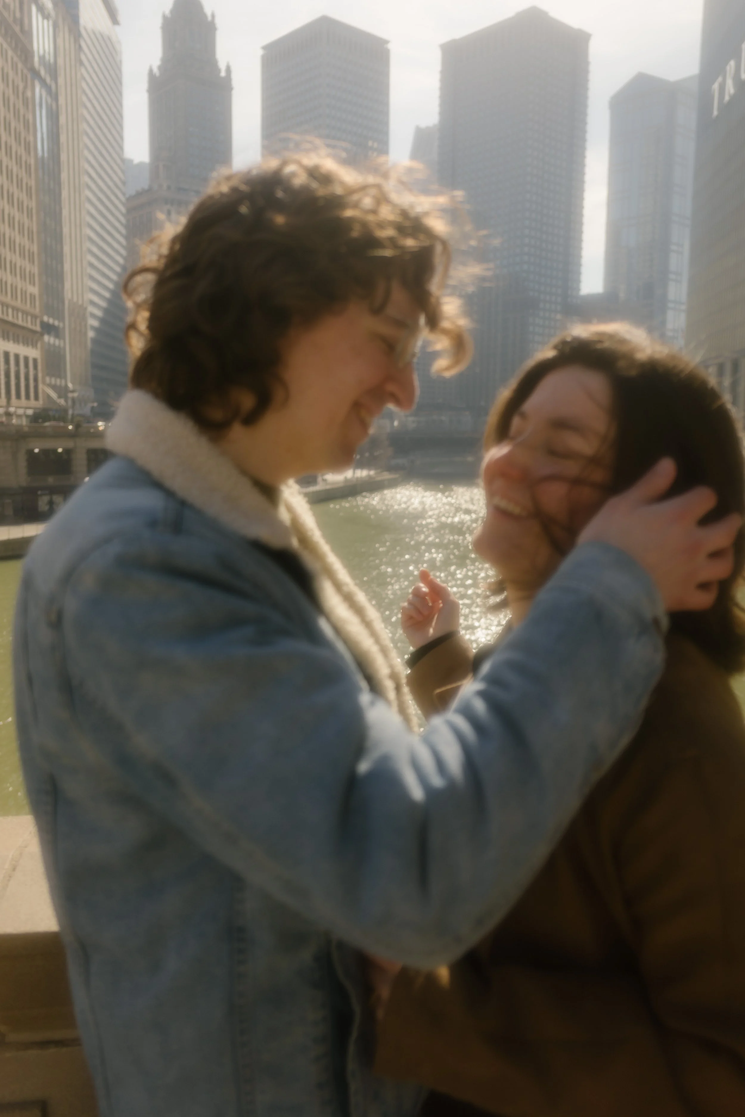 Close-up of couple smiling and brushing hair aside with wind blowing along the Chicago River