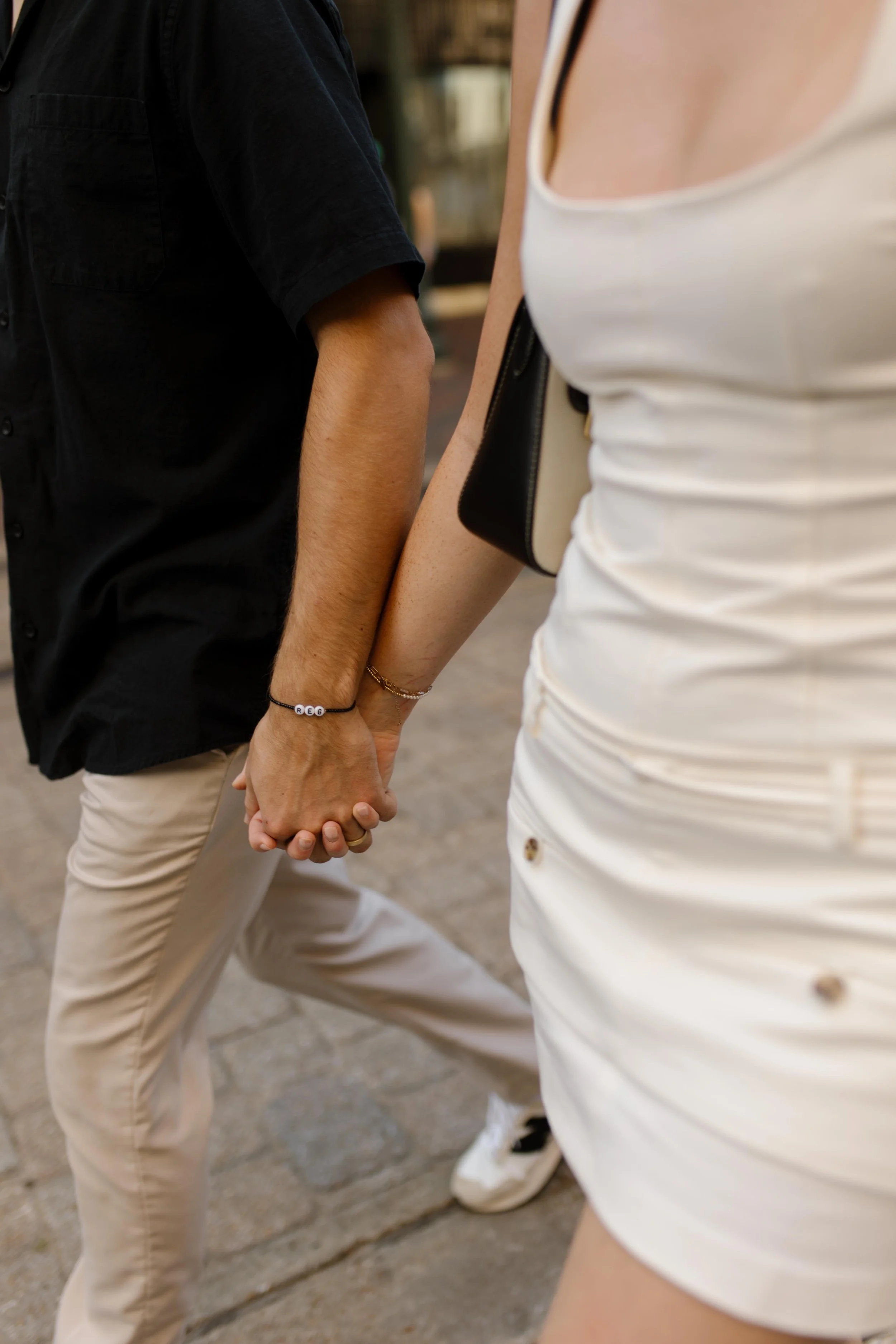 Close up of couple holding hands while walking through a downtown street in a candid engagement session