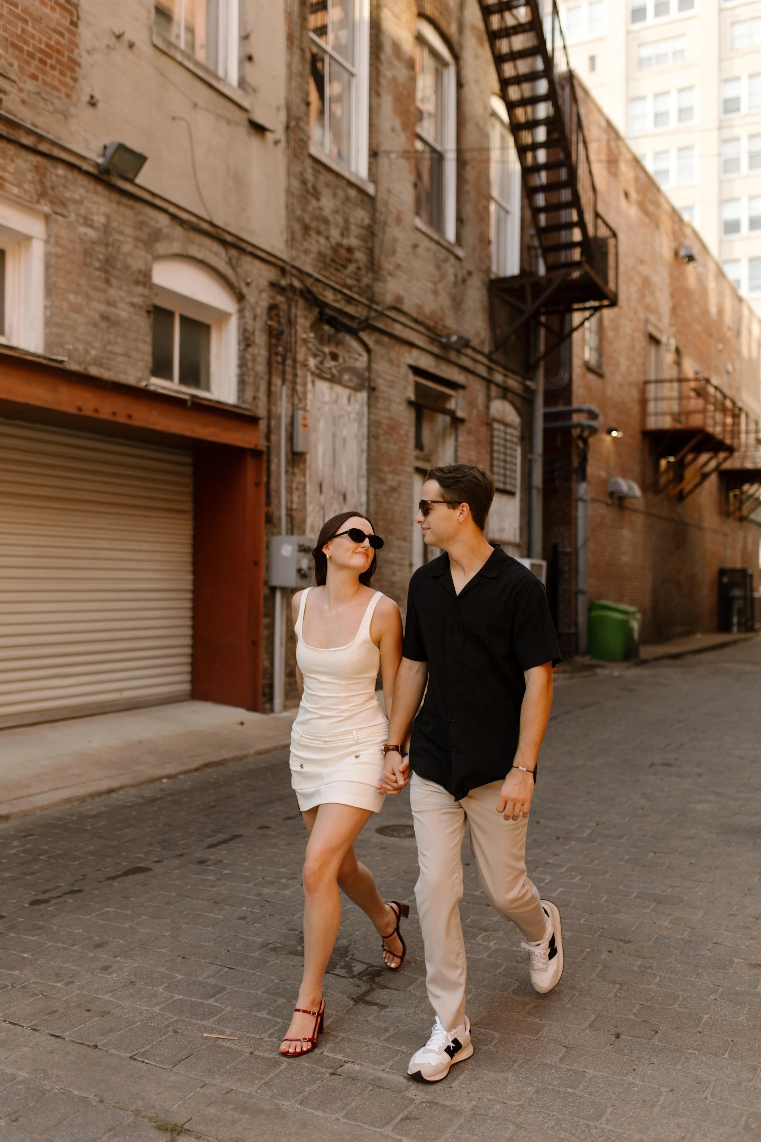  Couple walking together in an alley with warm light and city textures during new york city engagement photos 