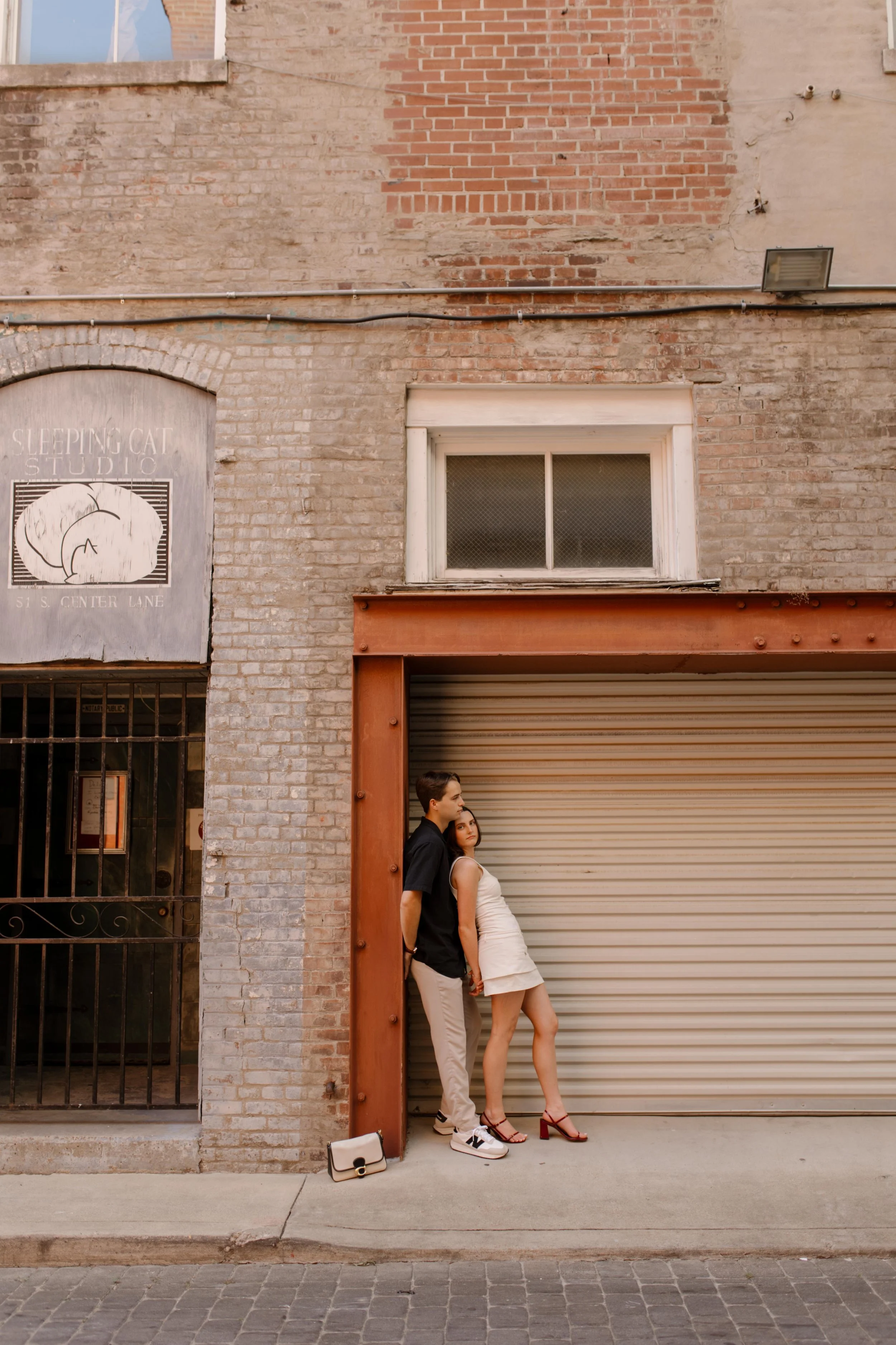 Couple leaning together against an industrial brick wall with a relaxed, editorial feel