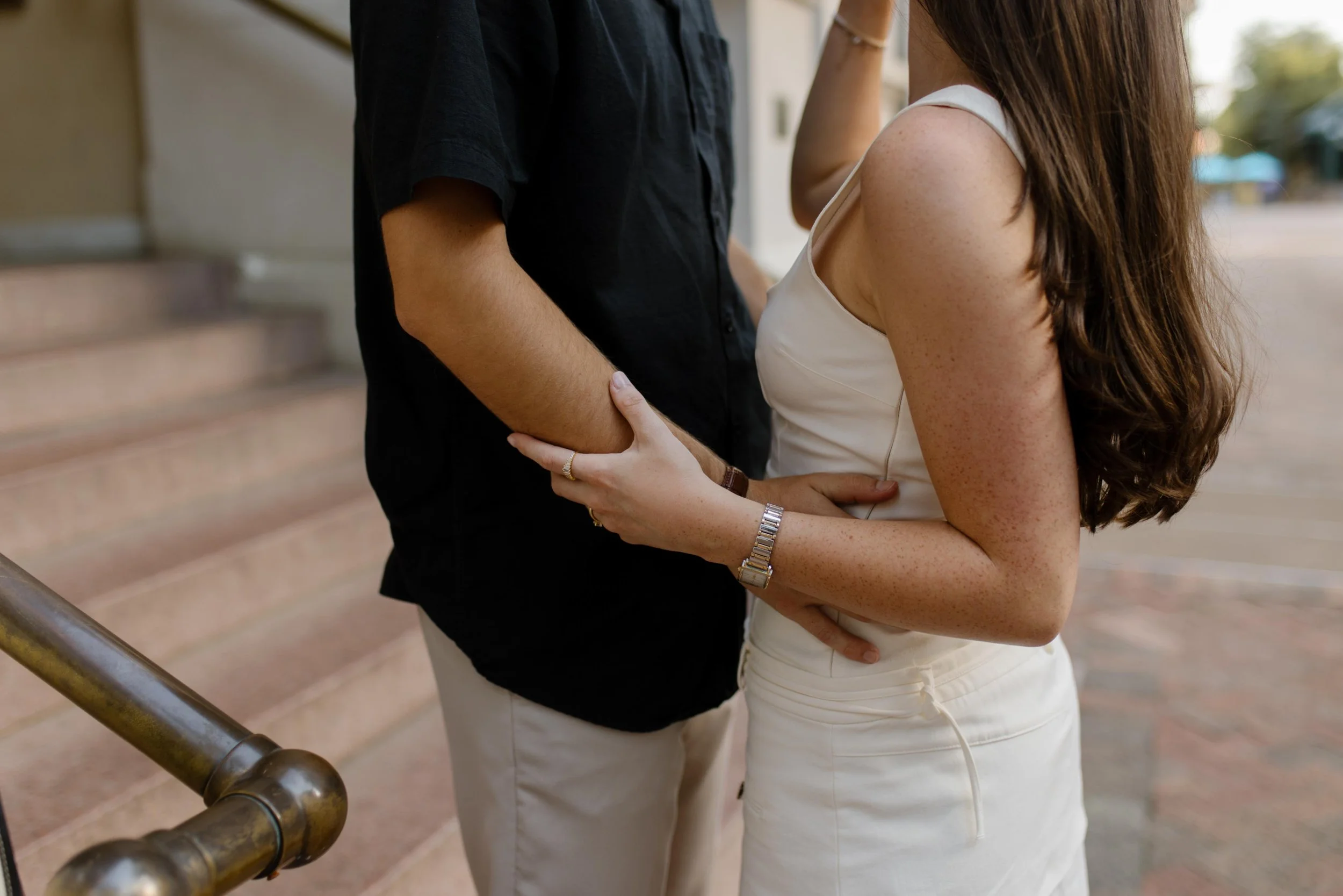 Close up of couple holding each other on city steps with soft natural light and intimate detail