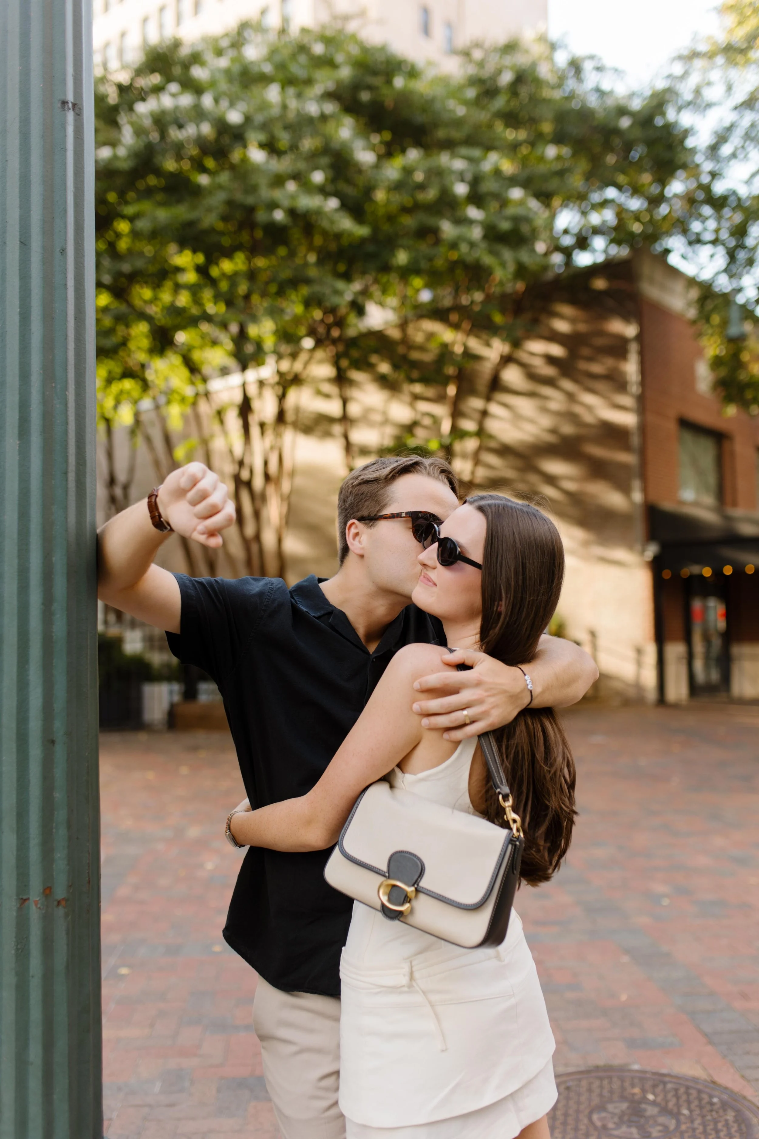Playful moment of couple embracing near a street corner with soft background blur and natural movement