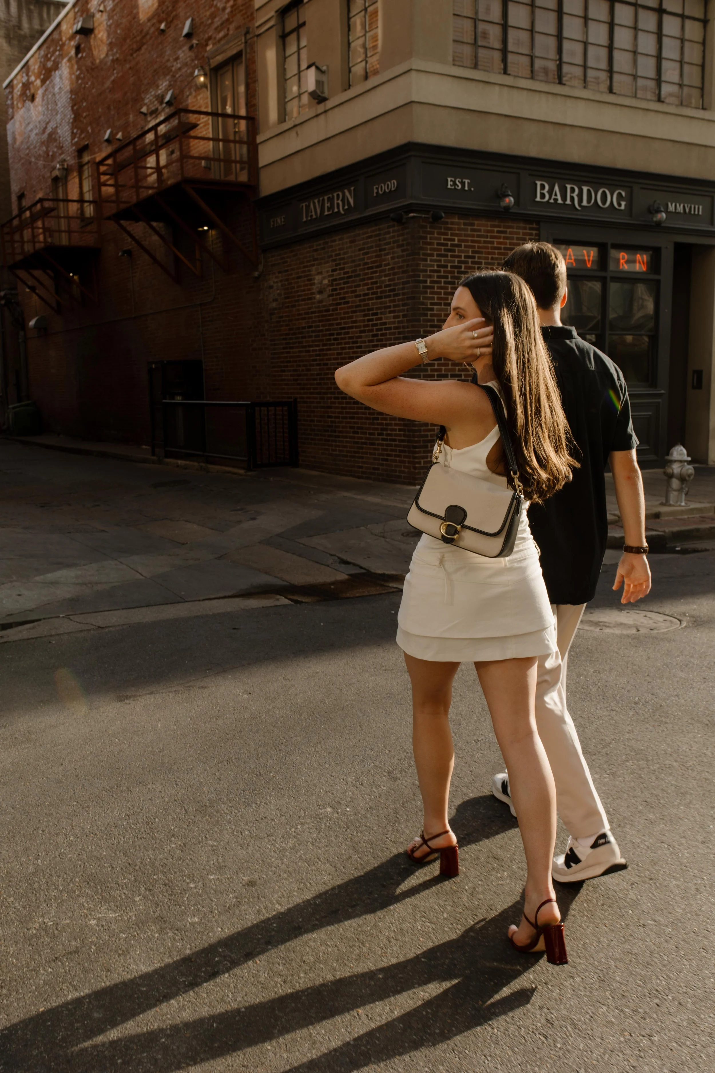 Couple walking across a city street with long shadows and warm evening light during new york city engagement photos